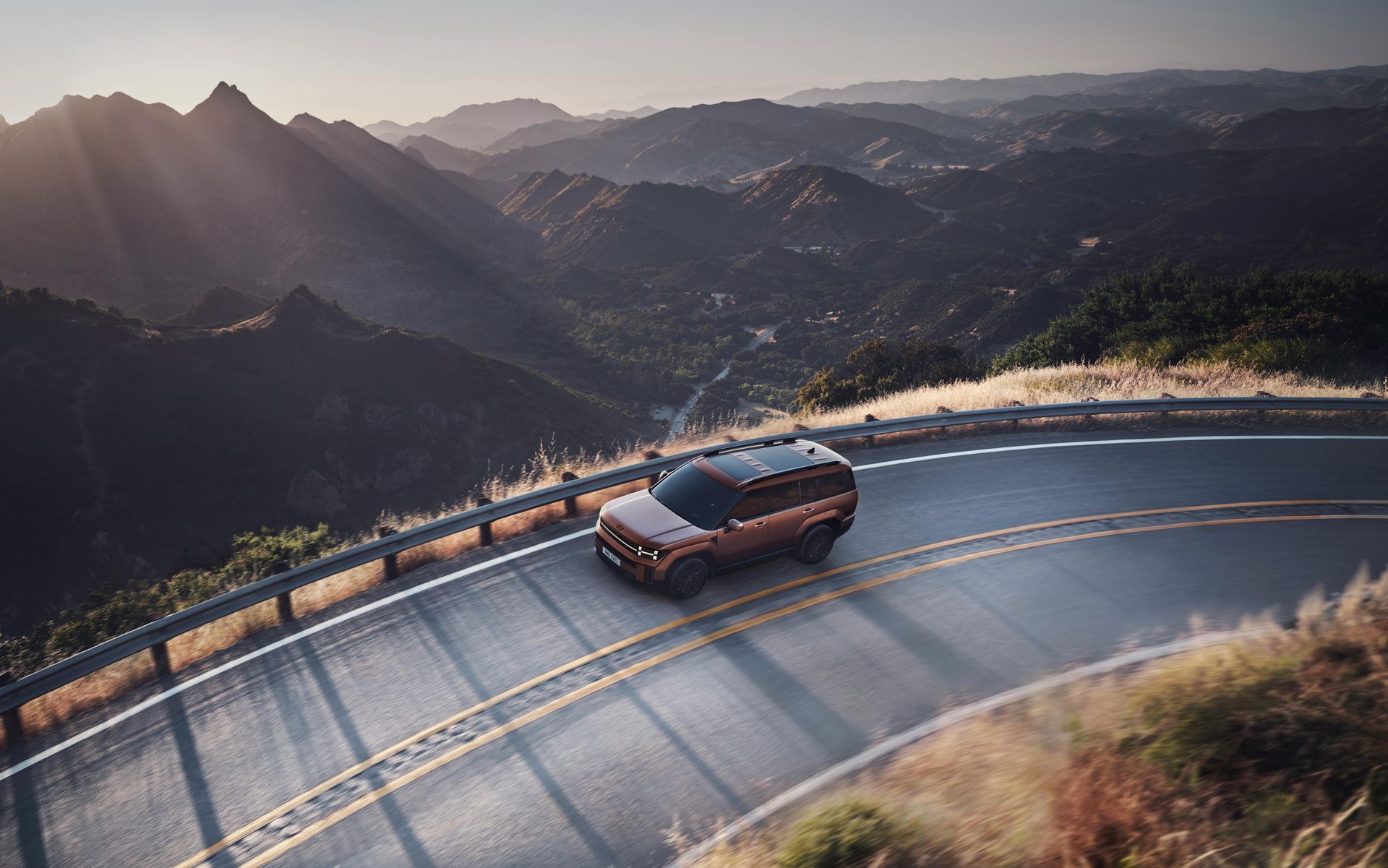 A car is driving down a curvy road in the mountains.