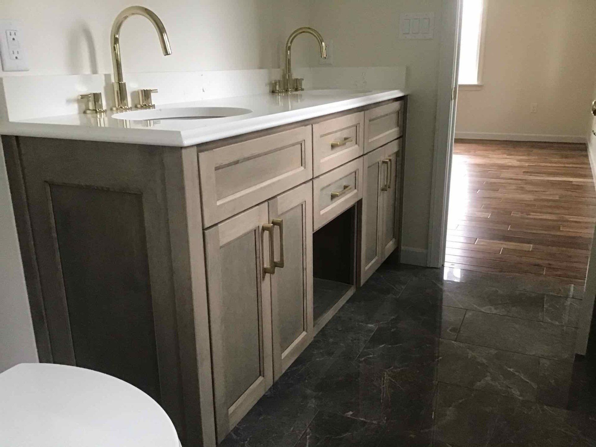 Bathroom vanity with gold fixtures, light cabinets, and white countertop.