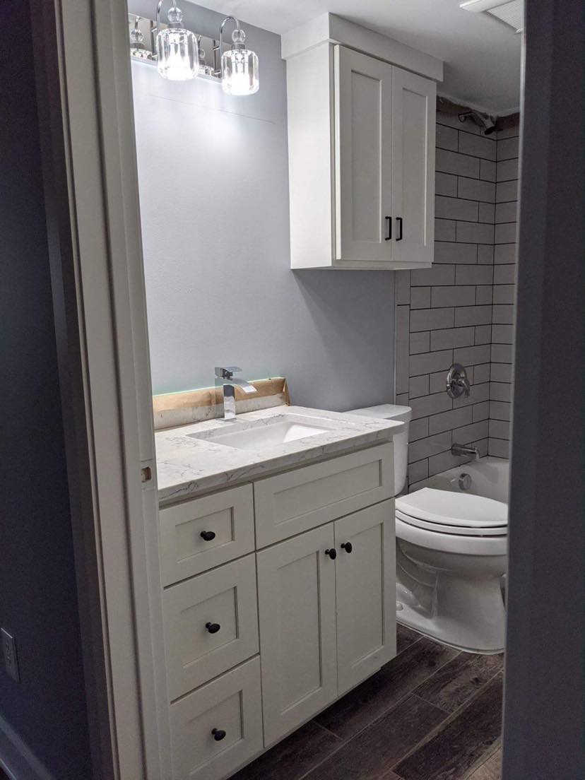Bathroom with white vanity, gray walls, and a shower with subway tile.