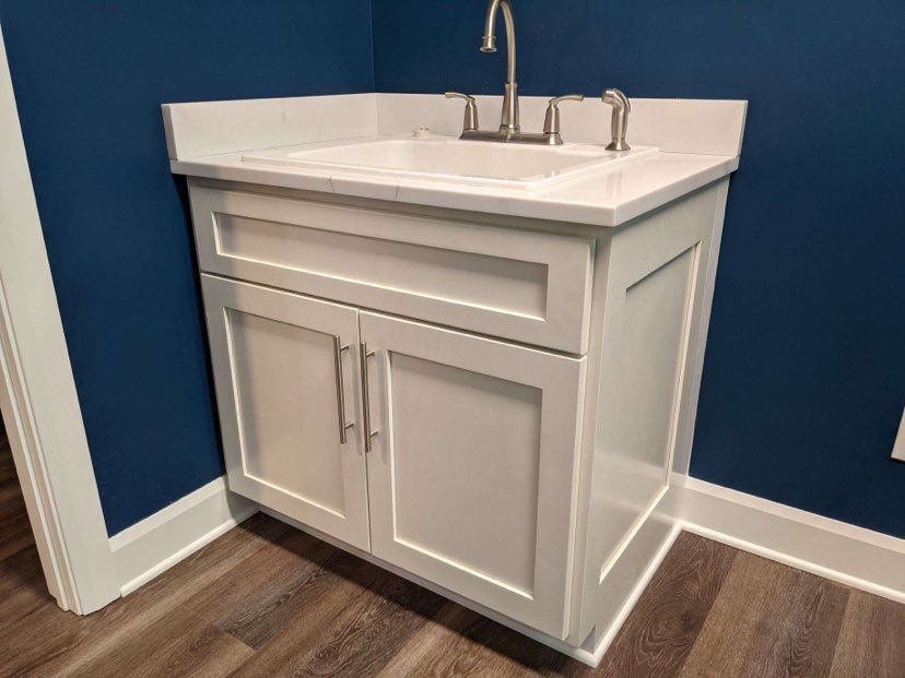White vanity cabinet with sink and faucet in a blue corner room.