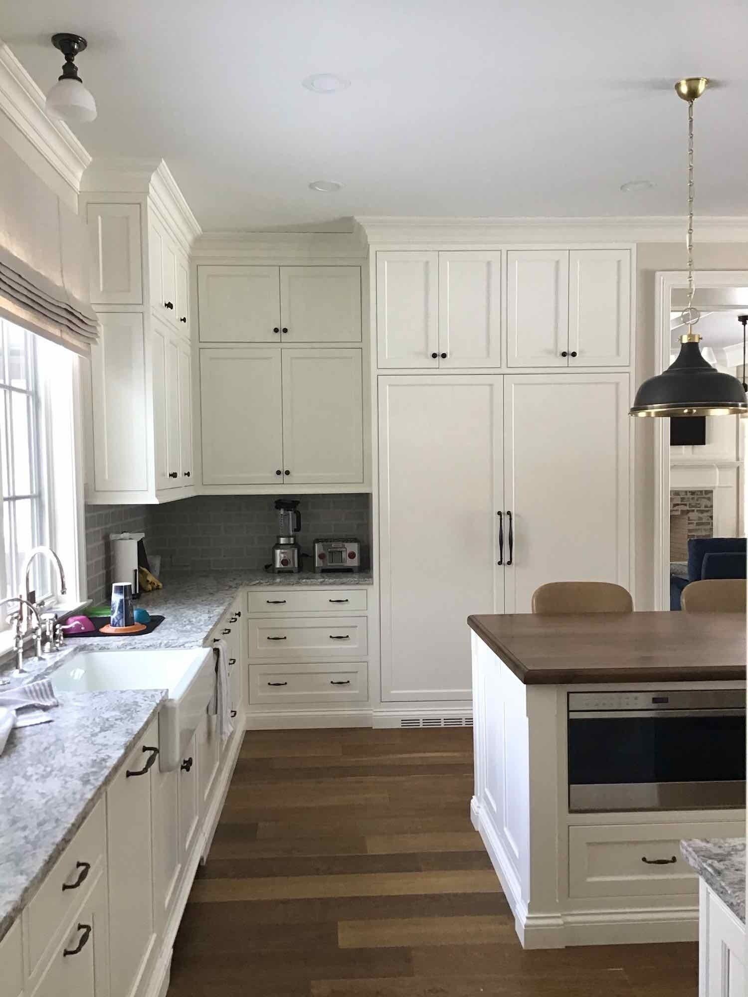 White kitchen with wood floor and island, cabinets, and appliances.