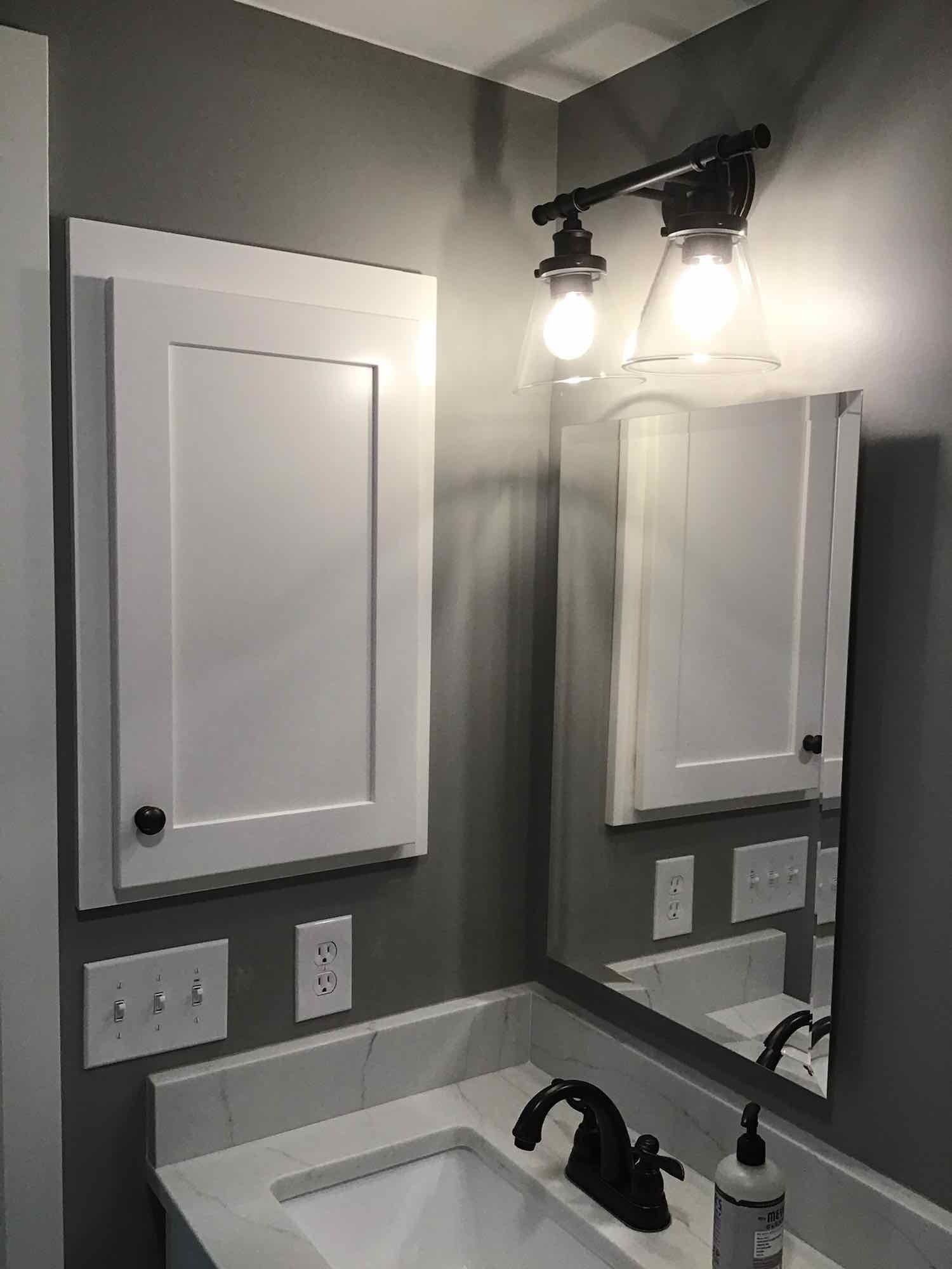 A bathroom with a sink , mirror and cabinets.