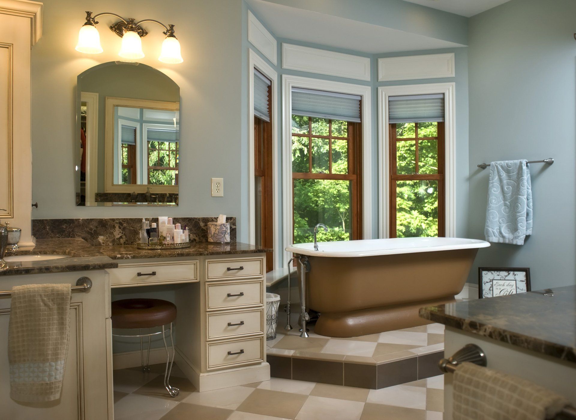 Bathroom with brown clawfoot tub, vanity with stool, bay window, and checkered floor.
