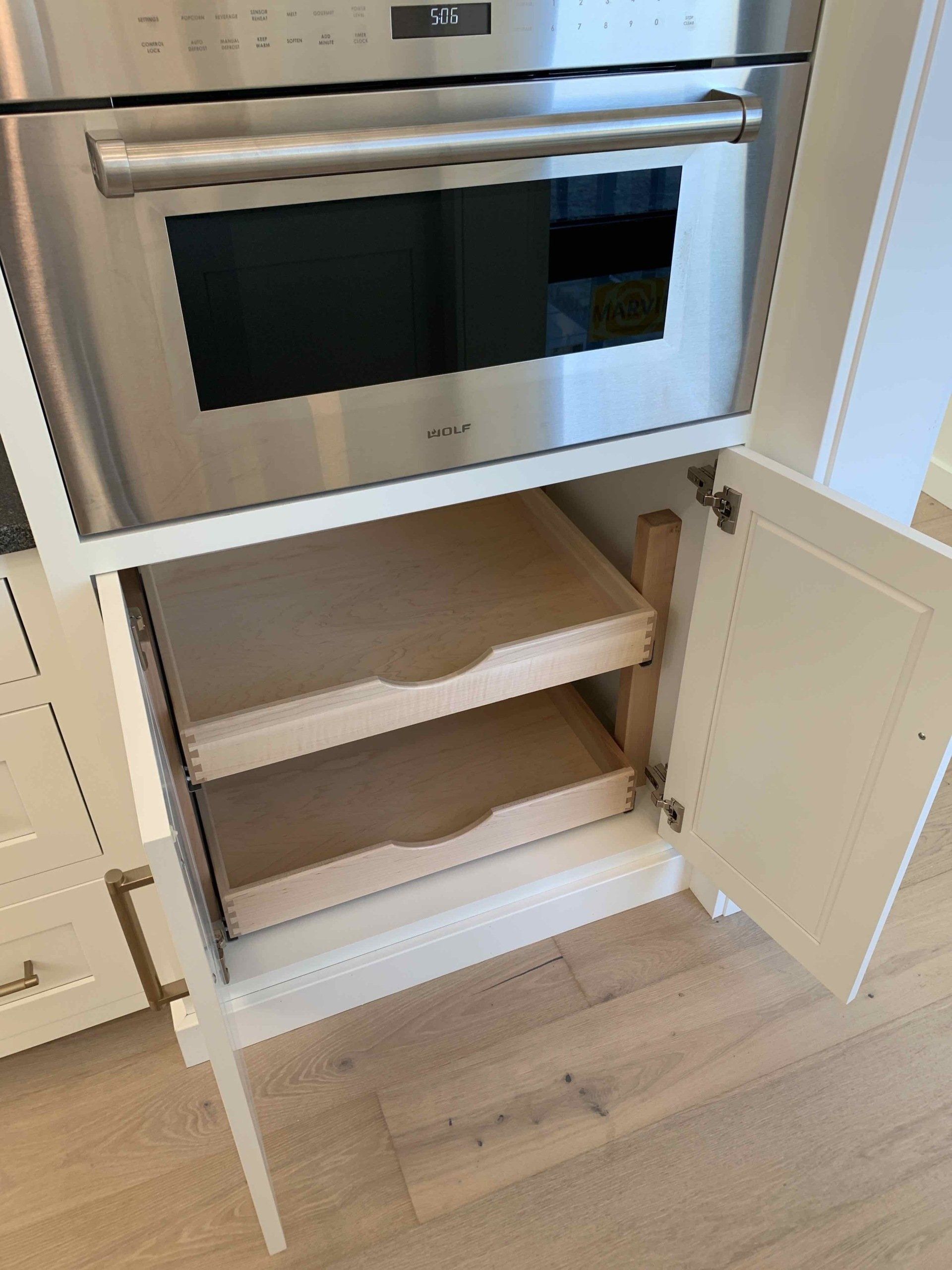 A kitchen with a stainless steel oven and drawers underneath it.