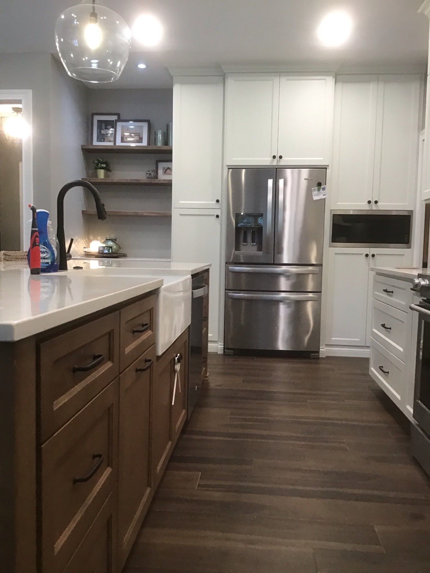 Kitchen with brown island cabinets, white countertops, stainless steel refrigerator, and dark wood floors.