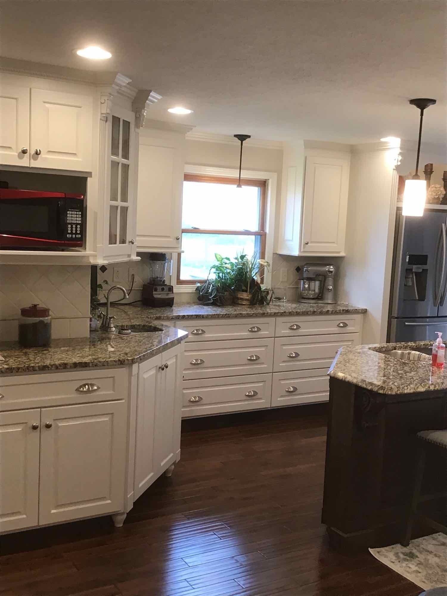White kitchen with granite countertops and dark wood floors.