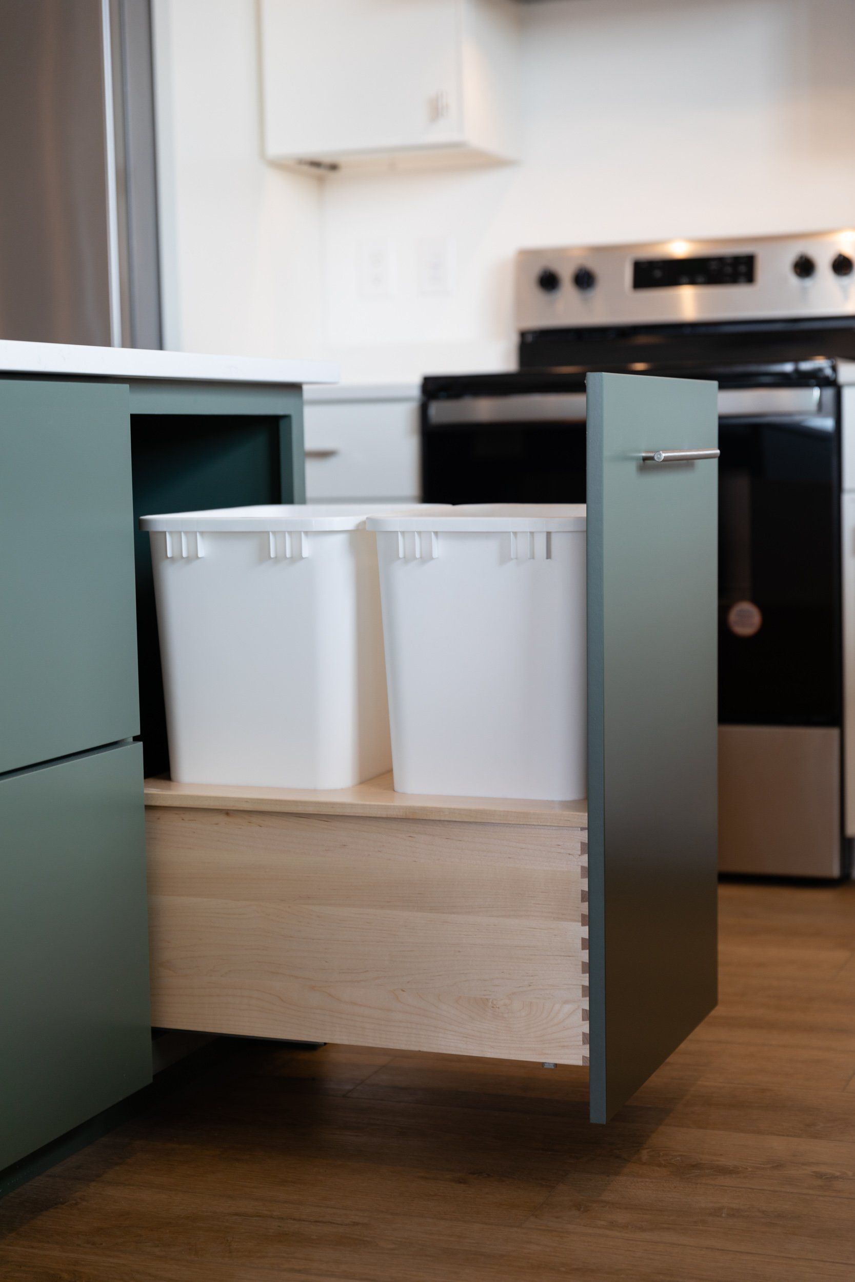 A kitchen with two trash cans in a drawer.