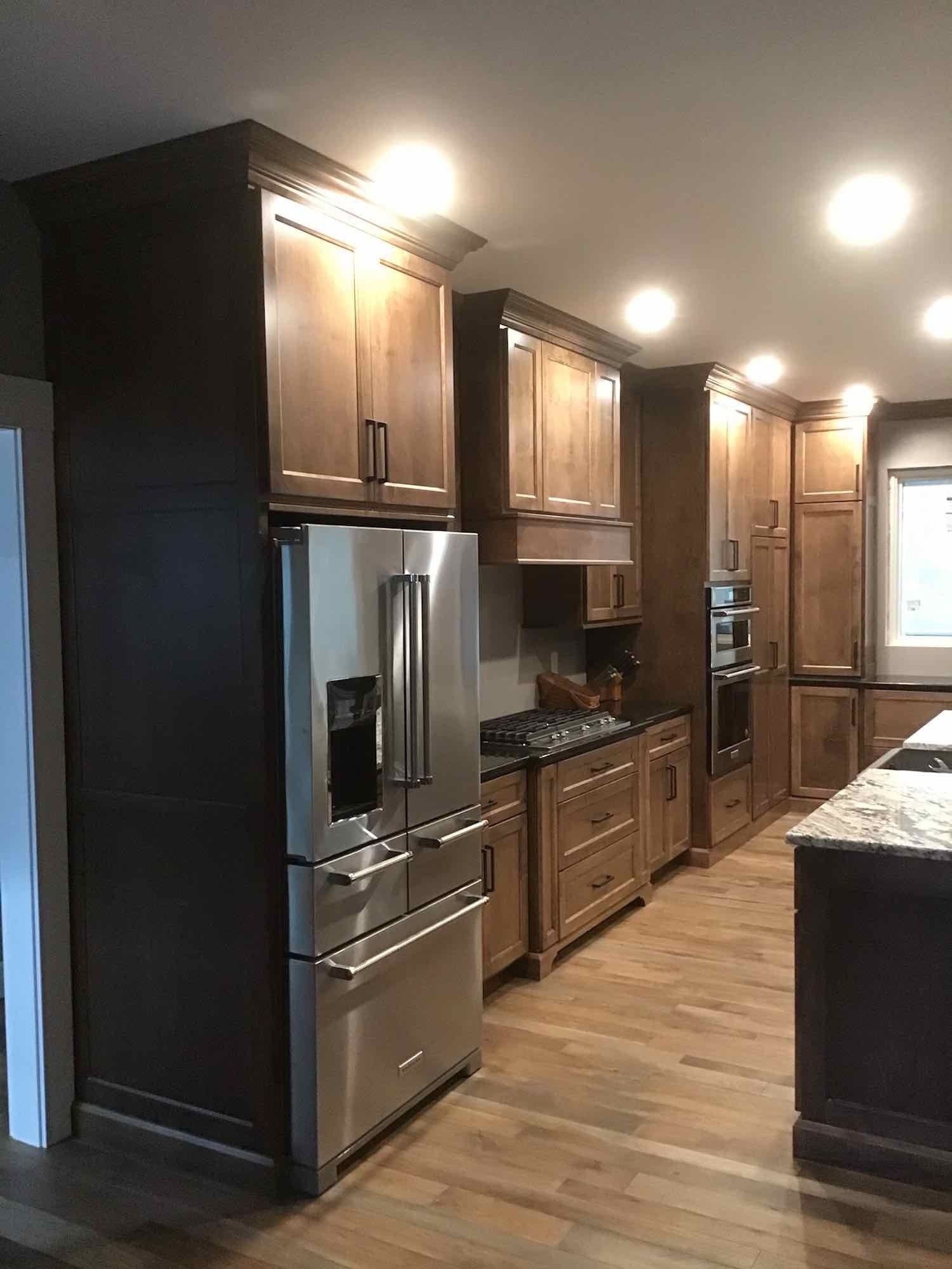 Kitchen with dark wood cabinets, stainless steel refrigerator, and hardwood floors.