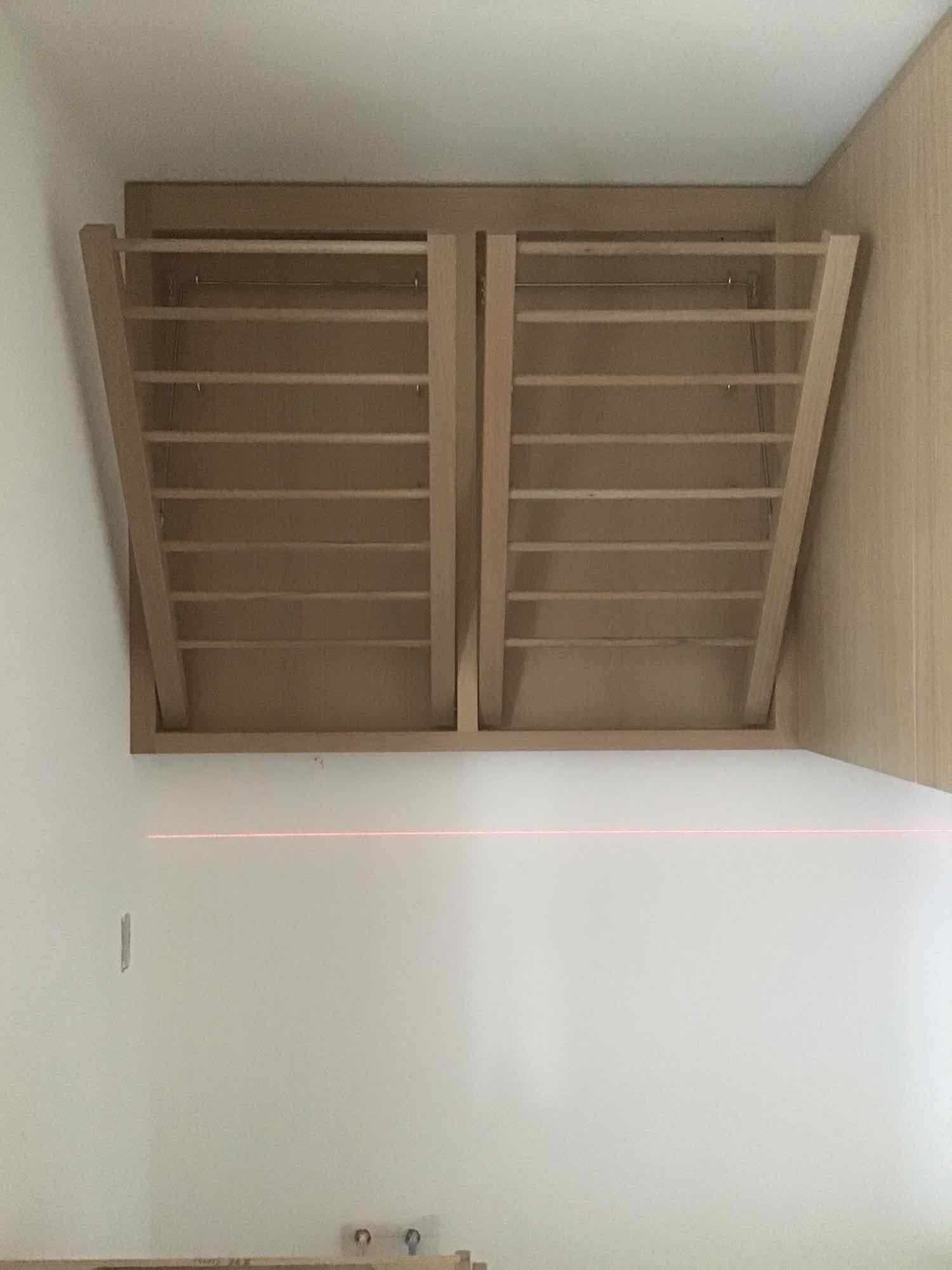 A wooden shelf is hanging from the ceiling in a room.