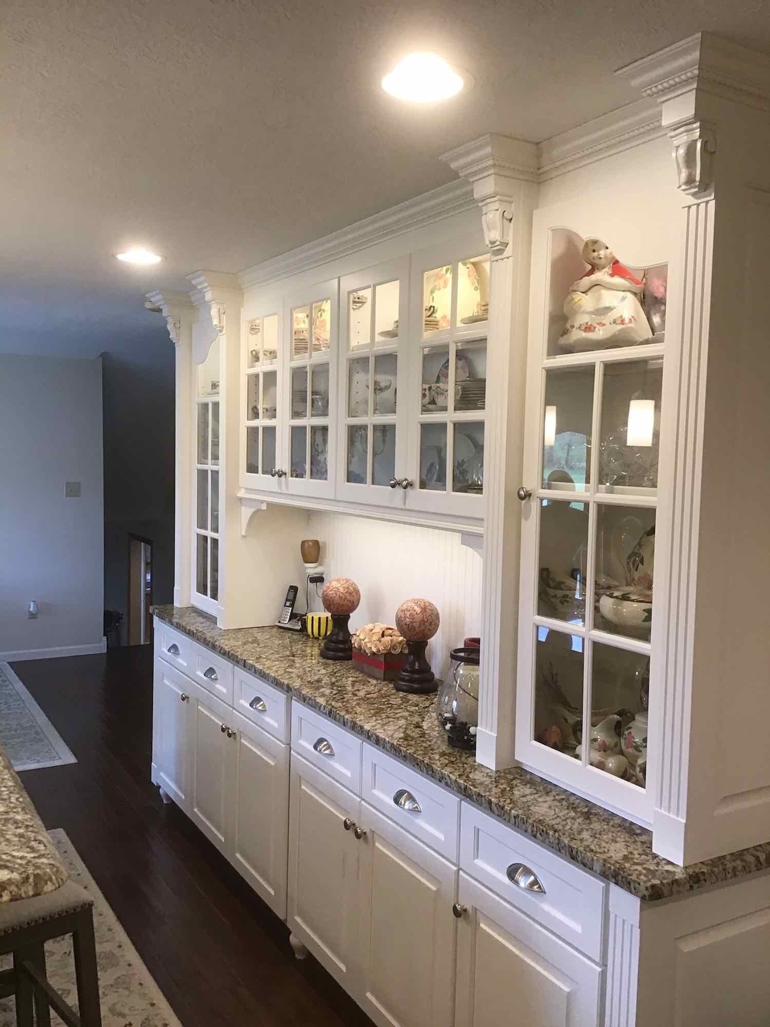 Built-in white kitchen cabinet with glass-front display shelves, countertop, and lower cabinets.
