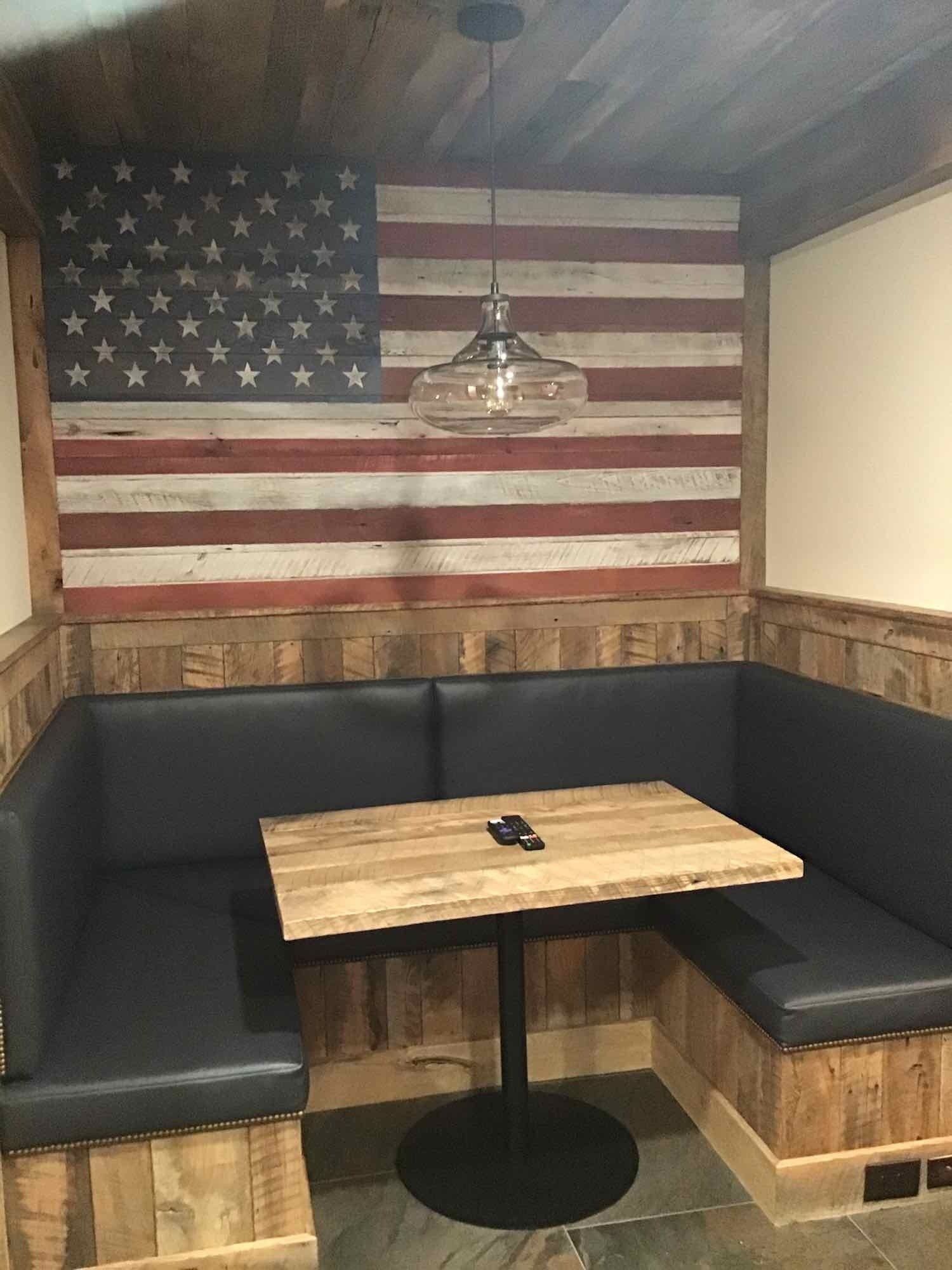 A booth with a table and an american flag on the wall.