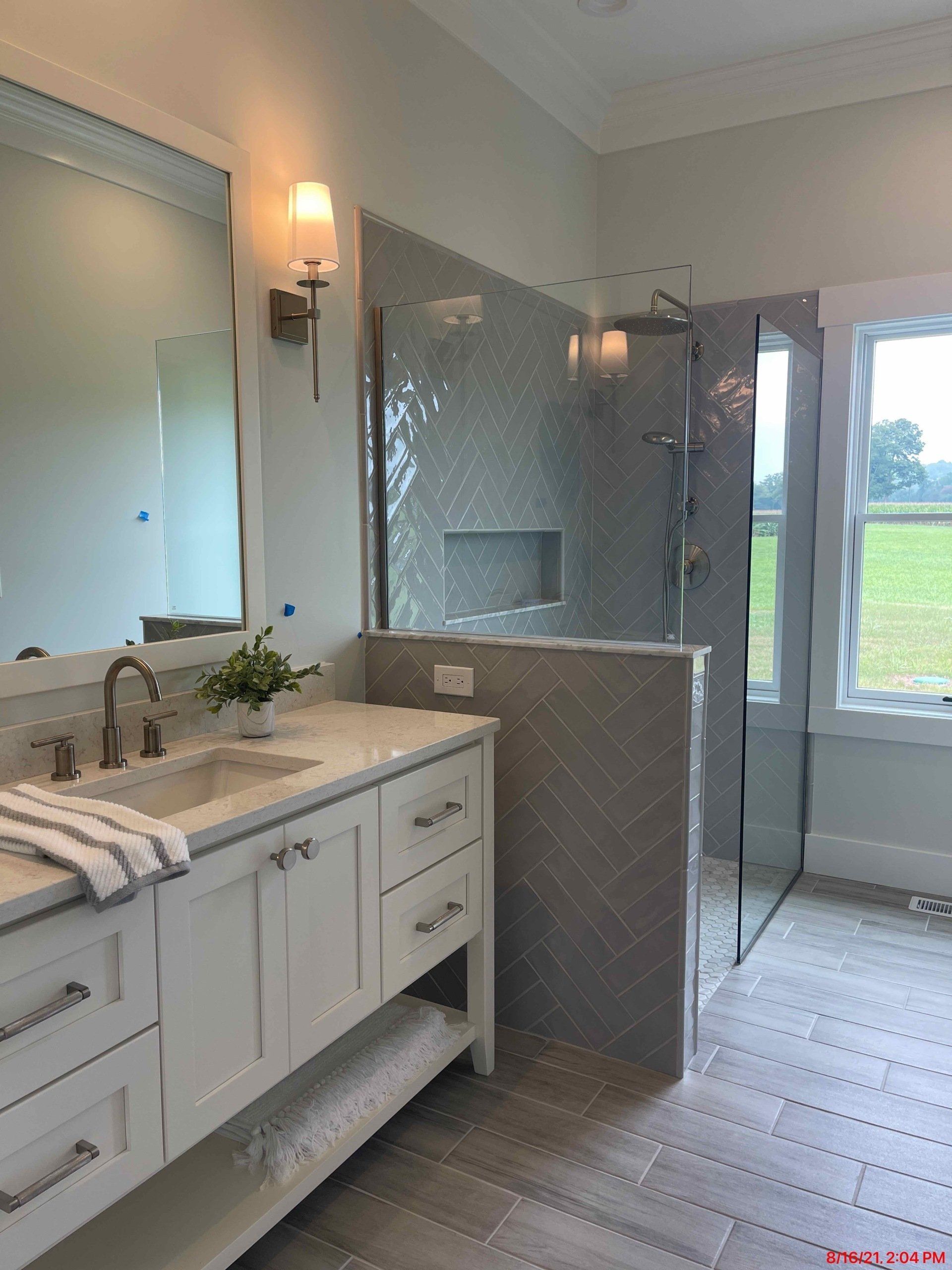 Bathroom with white vanity, gray tiled floor, and glass shower enclosure.