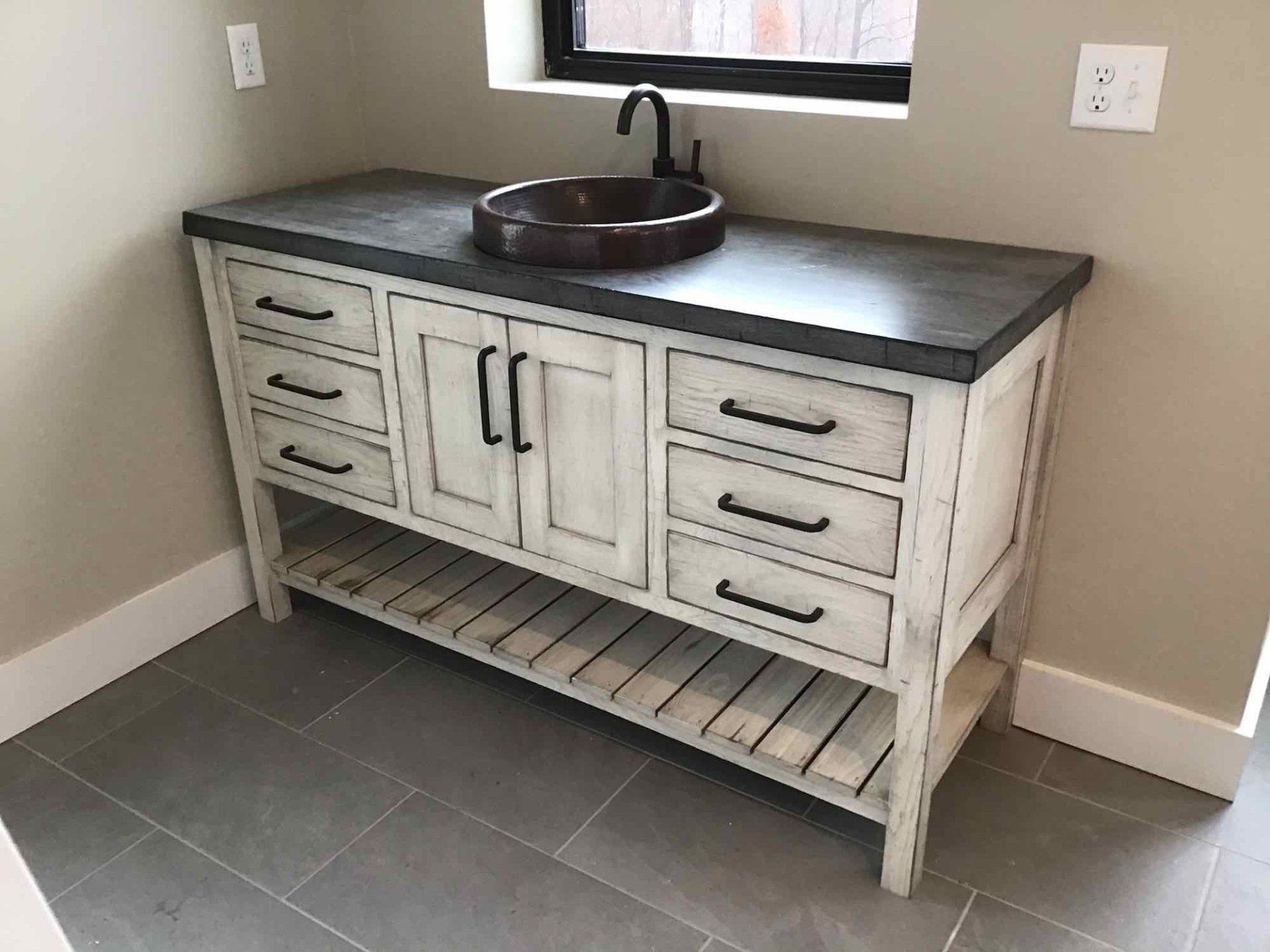Rustic white bathroom vanity with dark countertop, vessel sink, and matte black faucet.