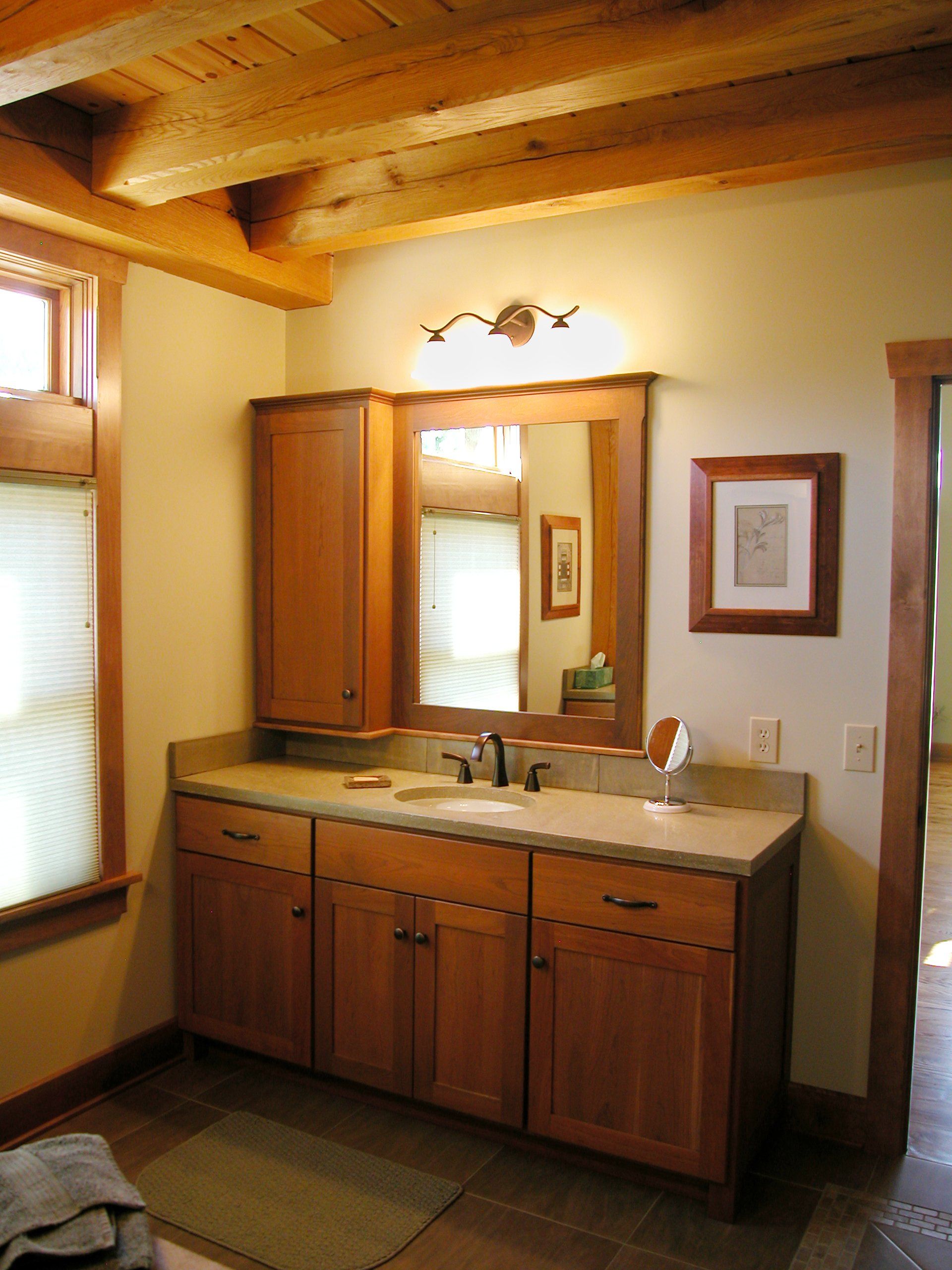 Bathroom with wooden vanity, mirror, and cabinet under a wood-beam ceiling.