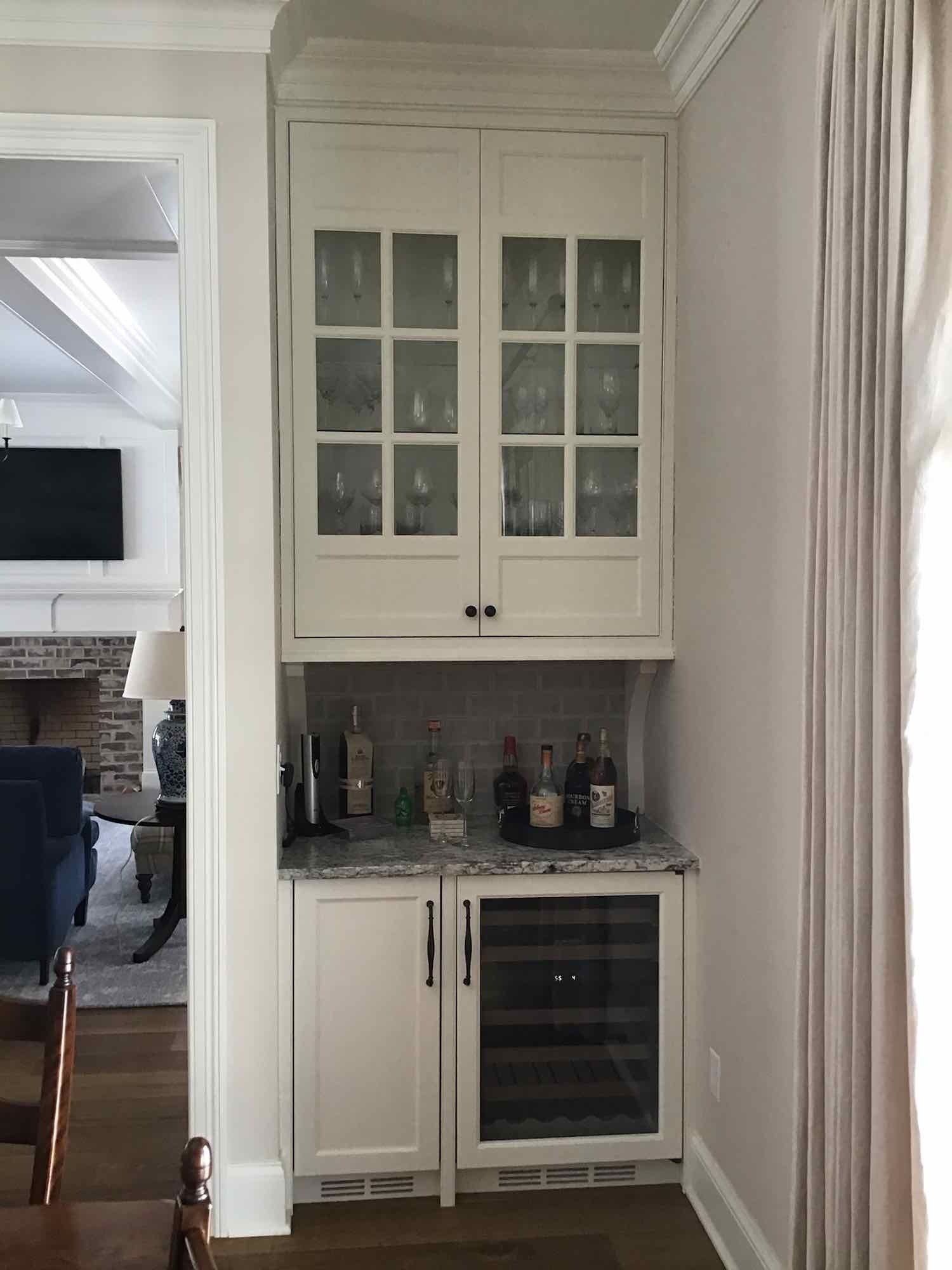 Built-in bar cabinet with glass-front upper doors, lower wine fridge, and countertop.