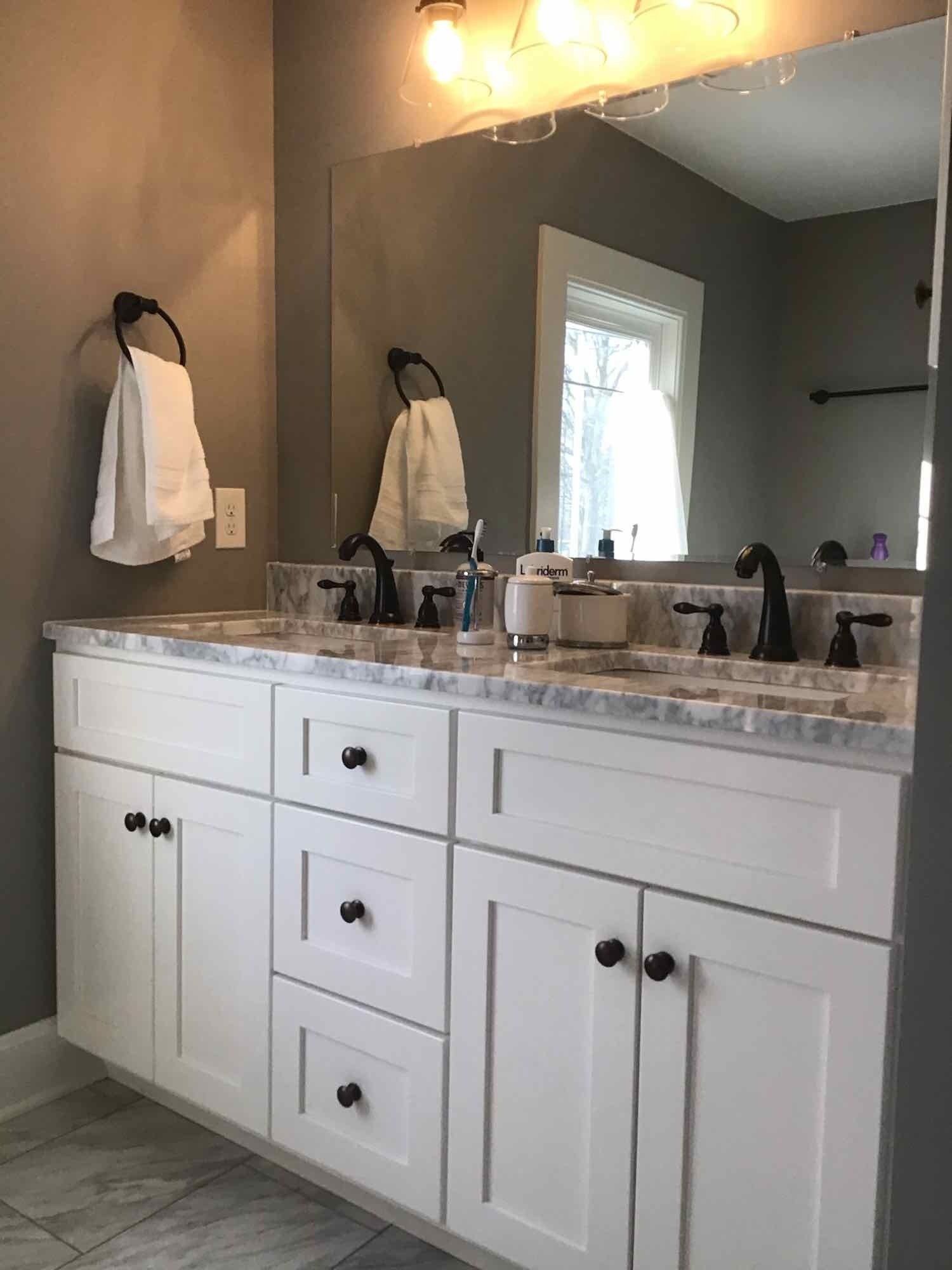 Bathroom with white vanity, double sinks, large mirror, and black fixtures.