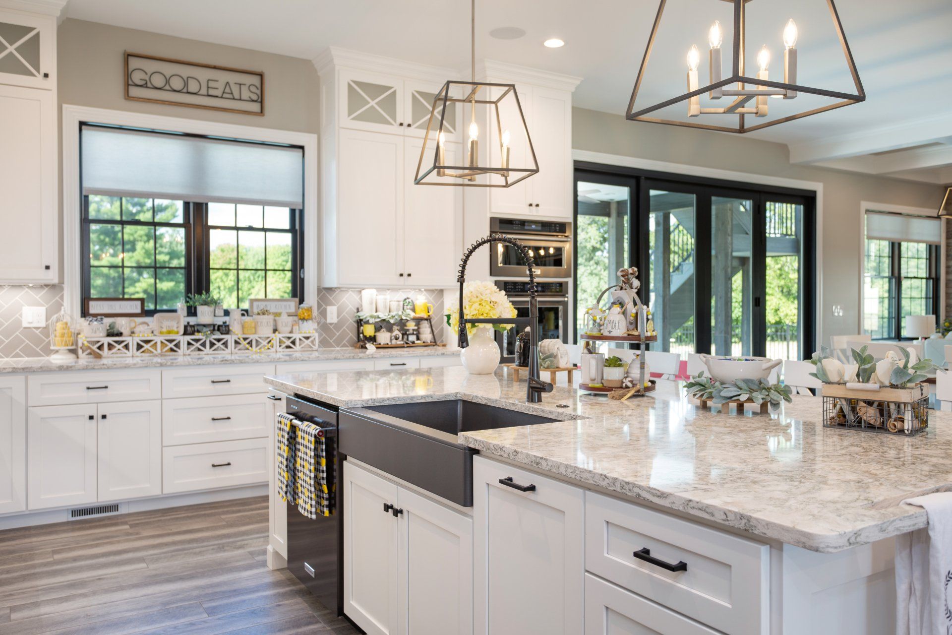 Modern white kitchen with a large island, black accents, and light gray countertops.