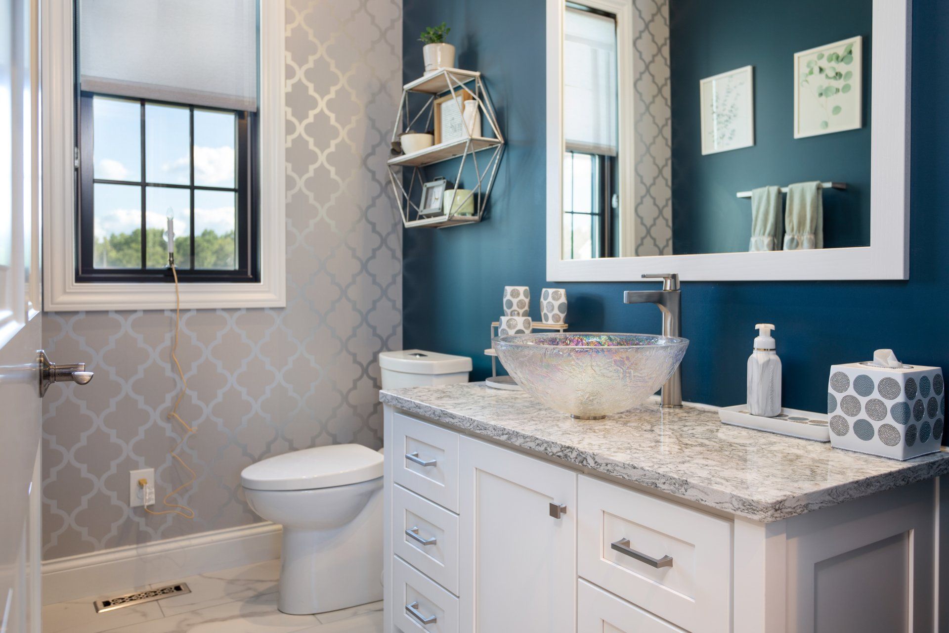 Bathroom with blue wall, white vanity, patterned gray wall.