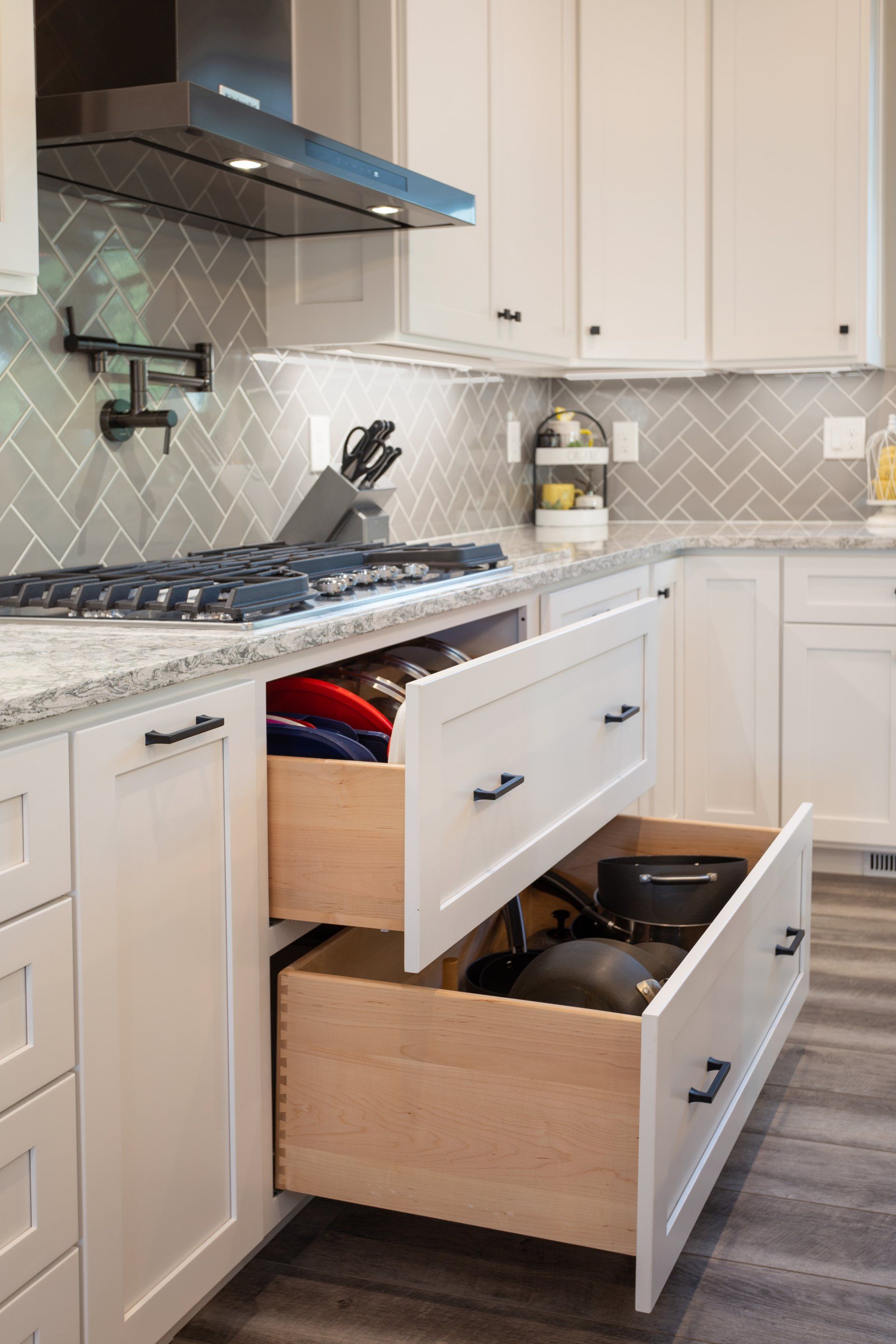 A kitchen with white cabinets and a wooden drawer open.