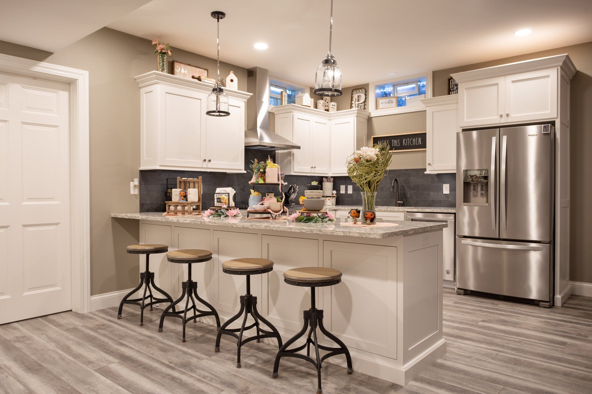 A beautiful kitchen with custom white cabinets, stainless steel appliances, a large island, and stools.