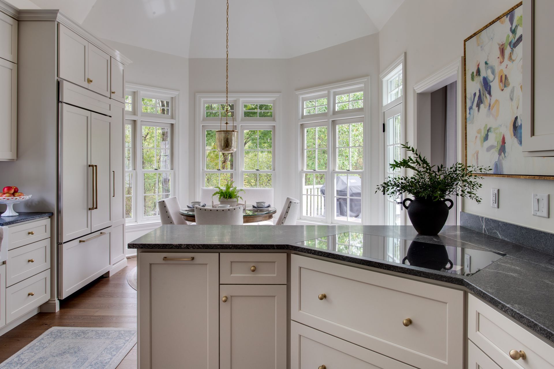 Kitchen with white cabinets, dark countertops, and a dining area with multiple windows.