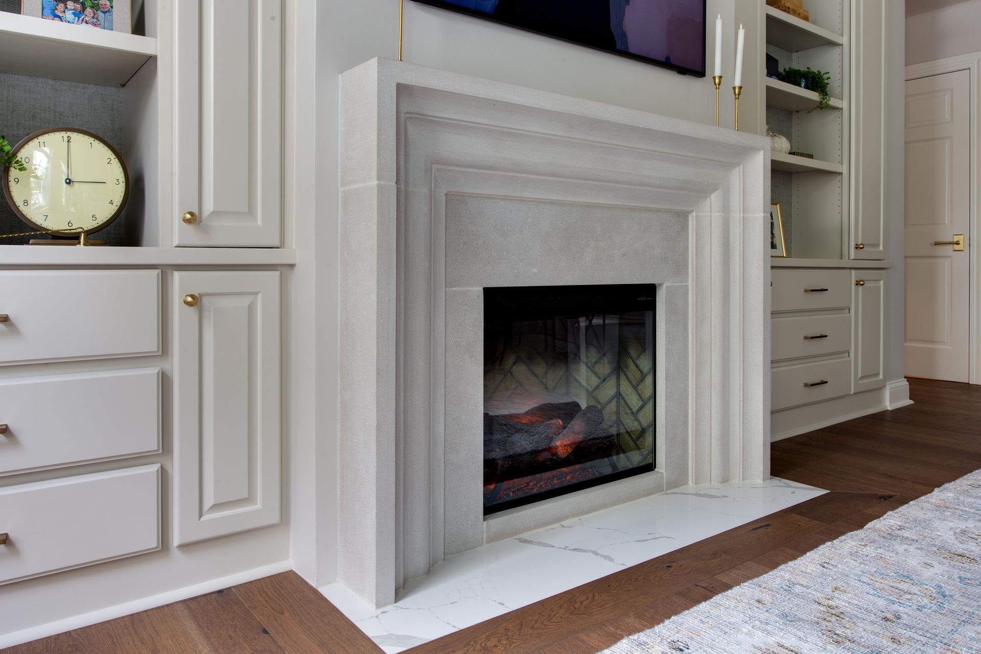 Fireplace with a gray stone mantel and built-in white cabinets.