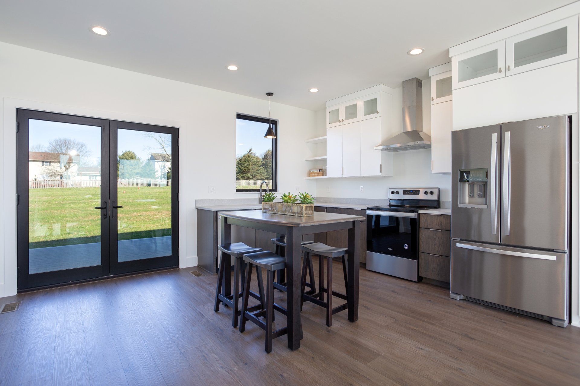 Modern kitchen with stainless steel appliances, dark island and seating, and French doors to a yard.
