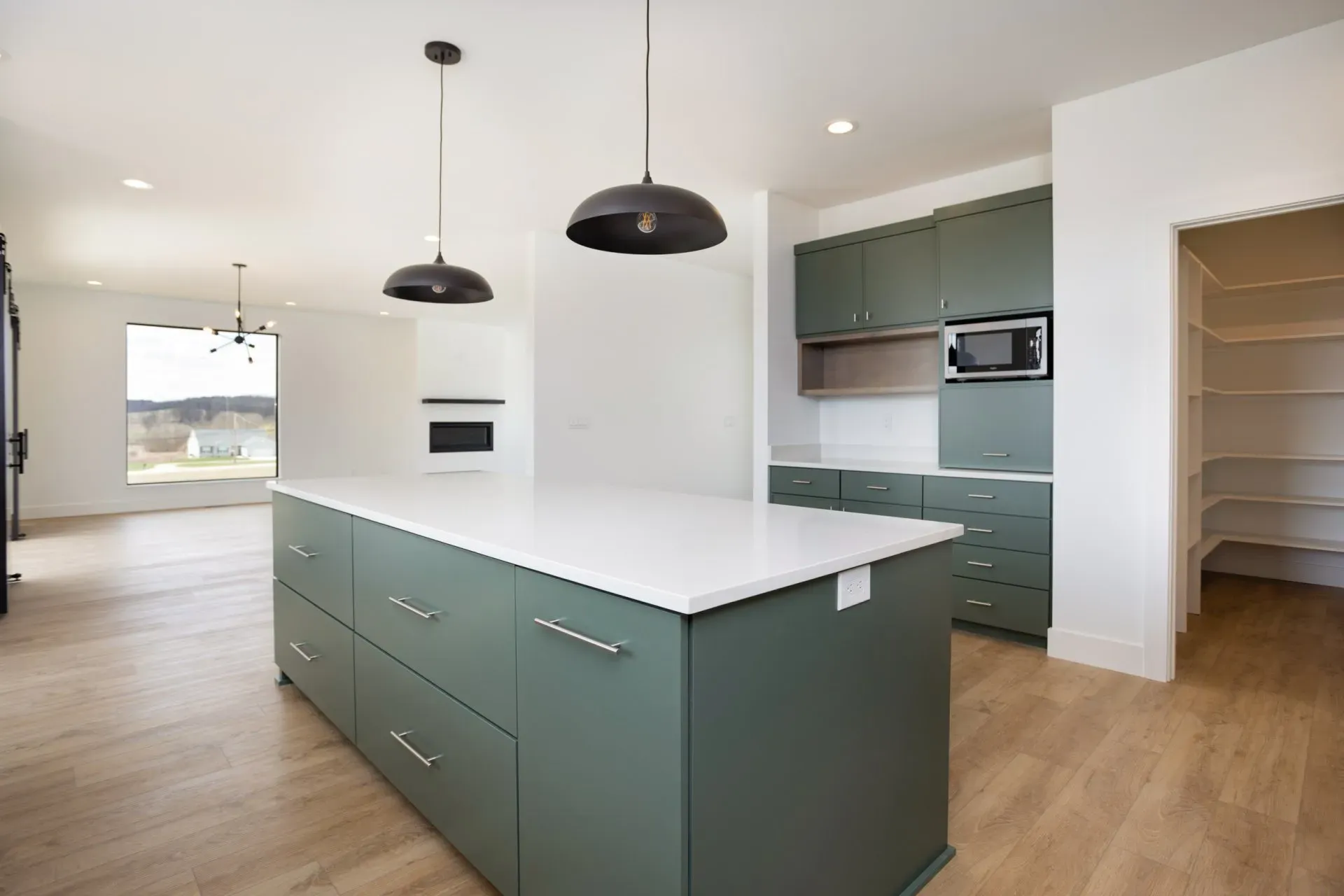 A kitchen with green cabinets and white counter tops.
