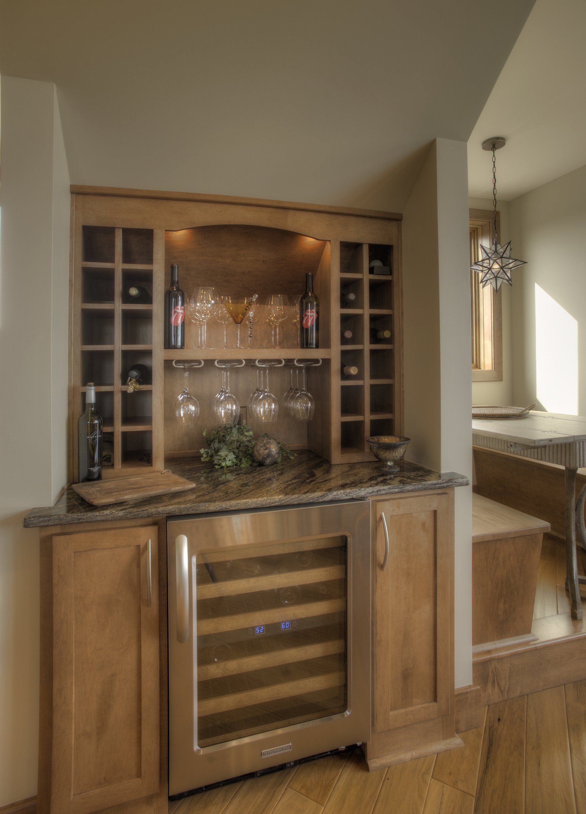 Wine bar cabinet with wine rack, cooler, and stemware storage in a home.