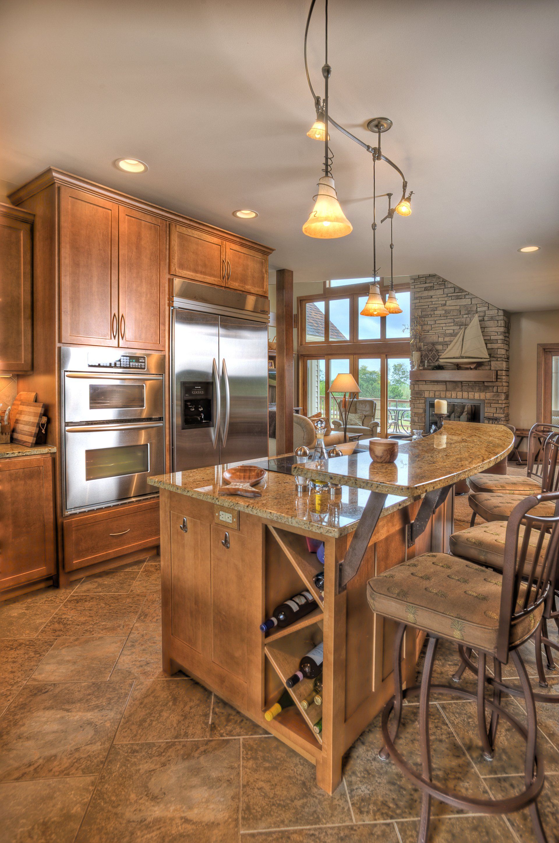 Wooden kitchen with island, cabinets, stainless steel appliances, and a granite countertop with seating.