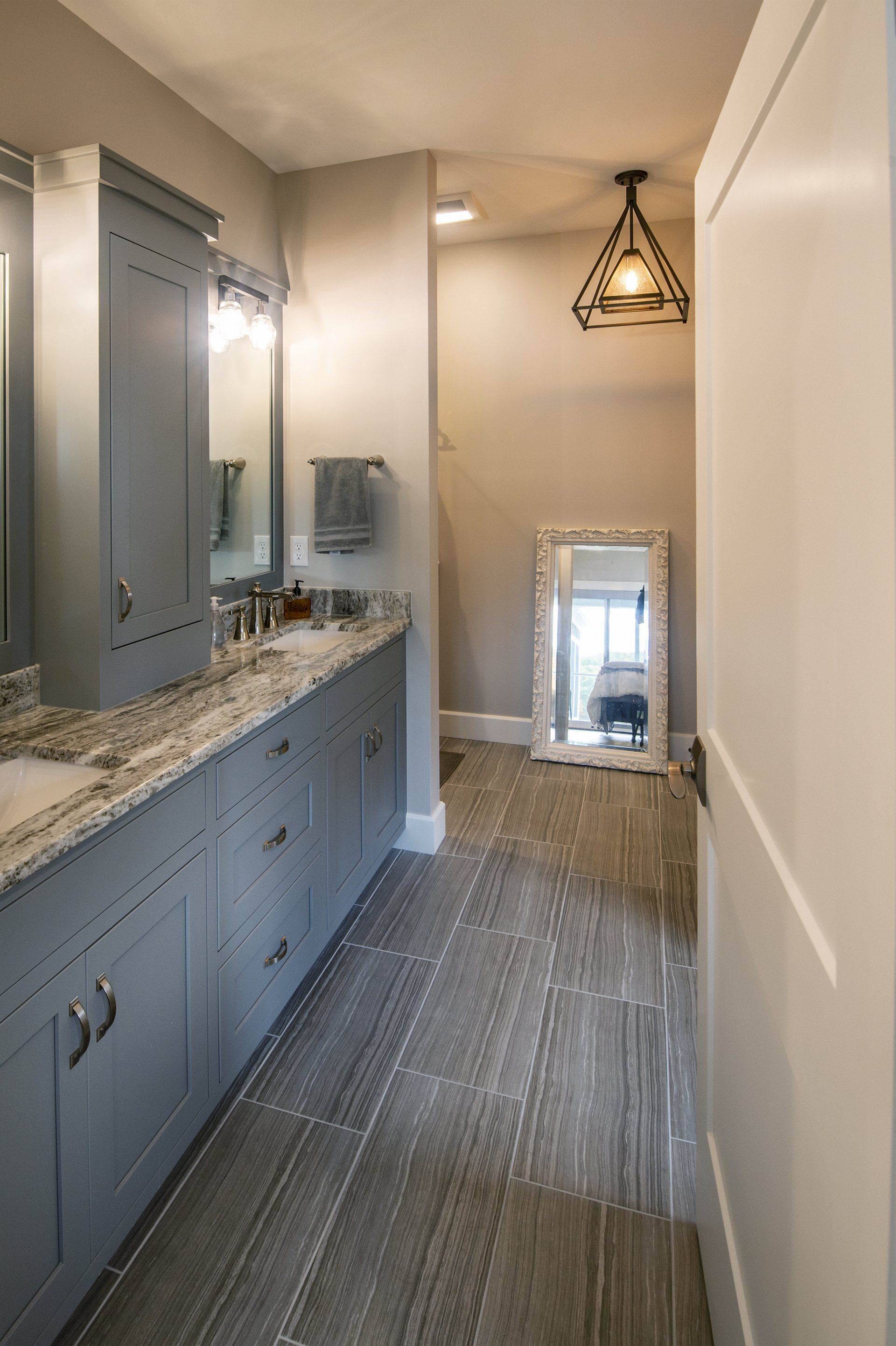 Gray and white bathroom with long vanity, a large mirror, and tiled floor.