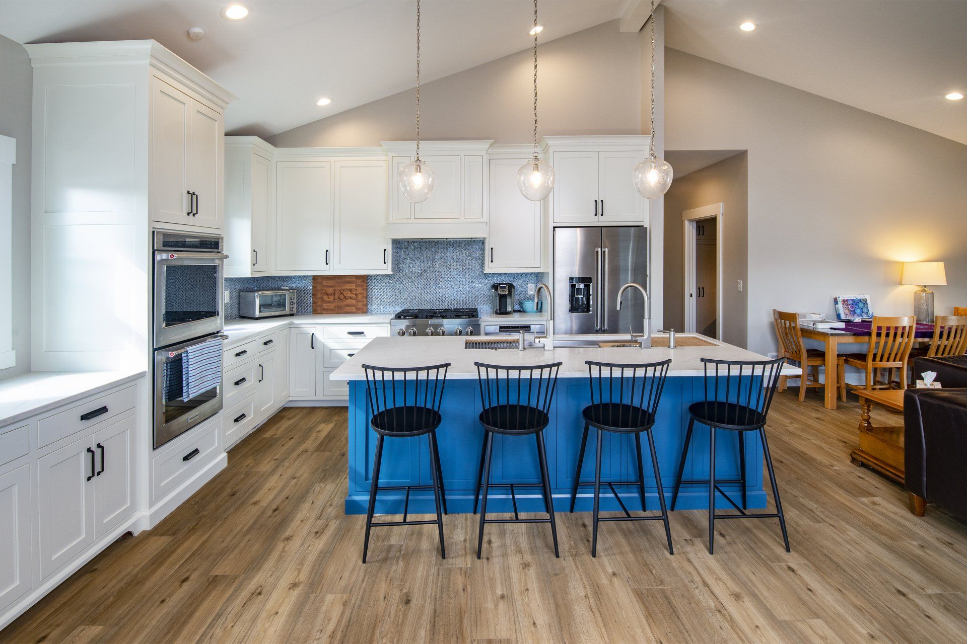 Bright kitchen with blue island and white cabinets. Wooden floor.