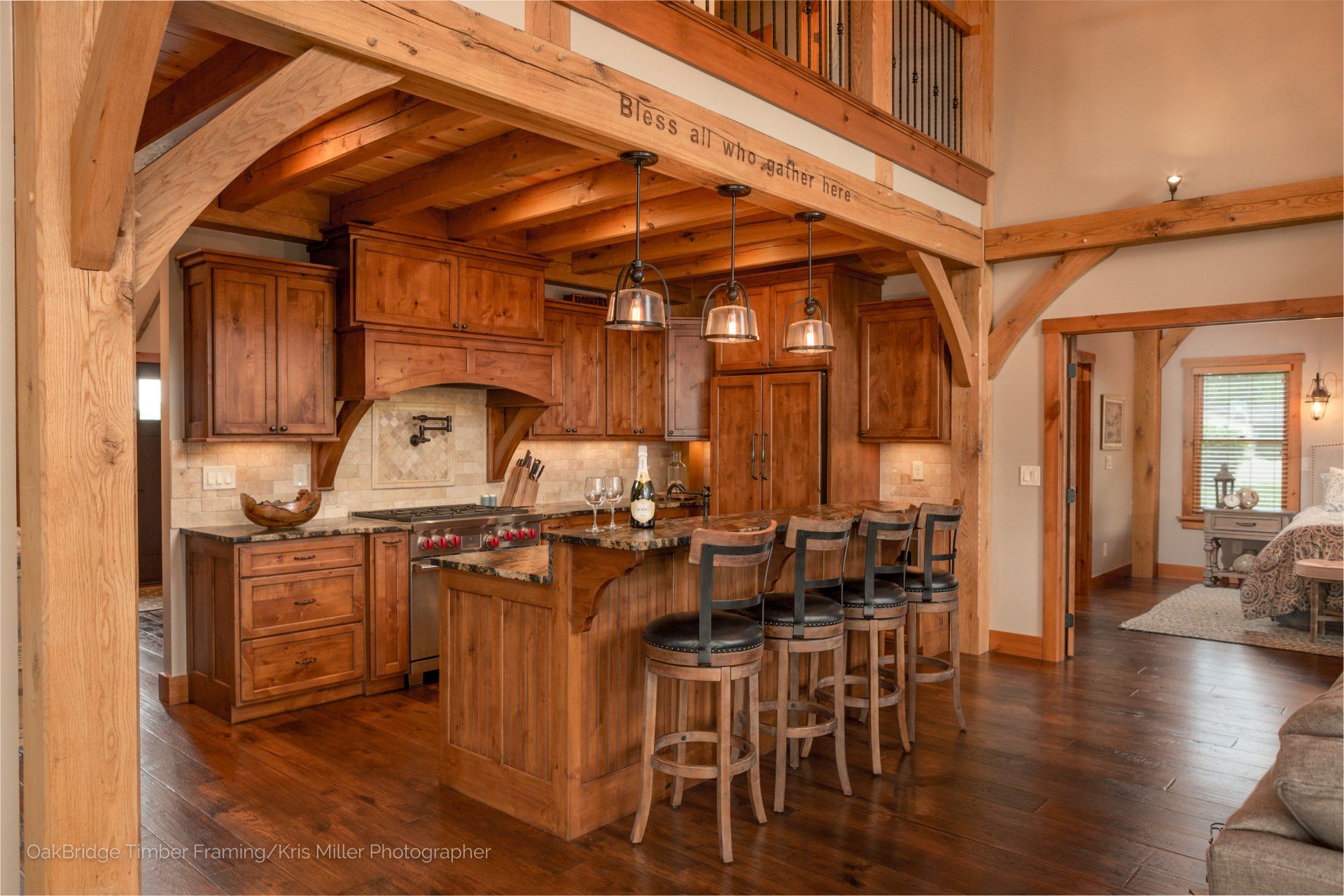 Kitchen with wood cabinetry, island with bar stools, and open beams.