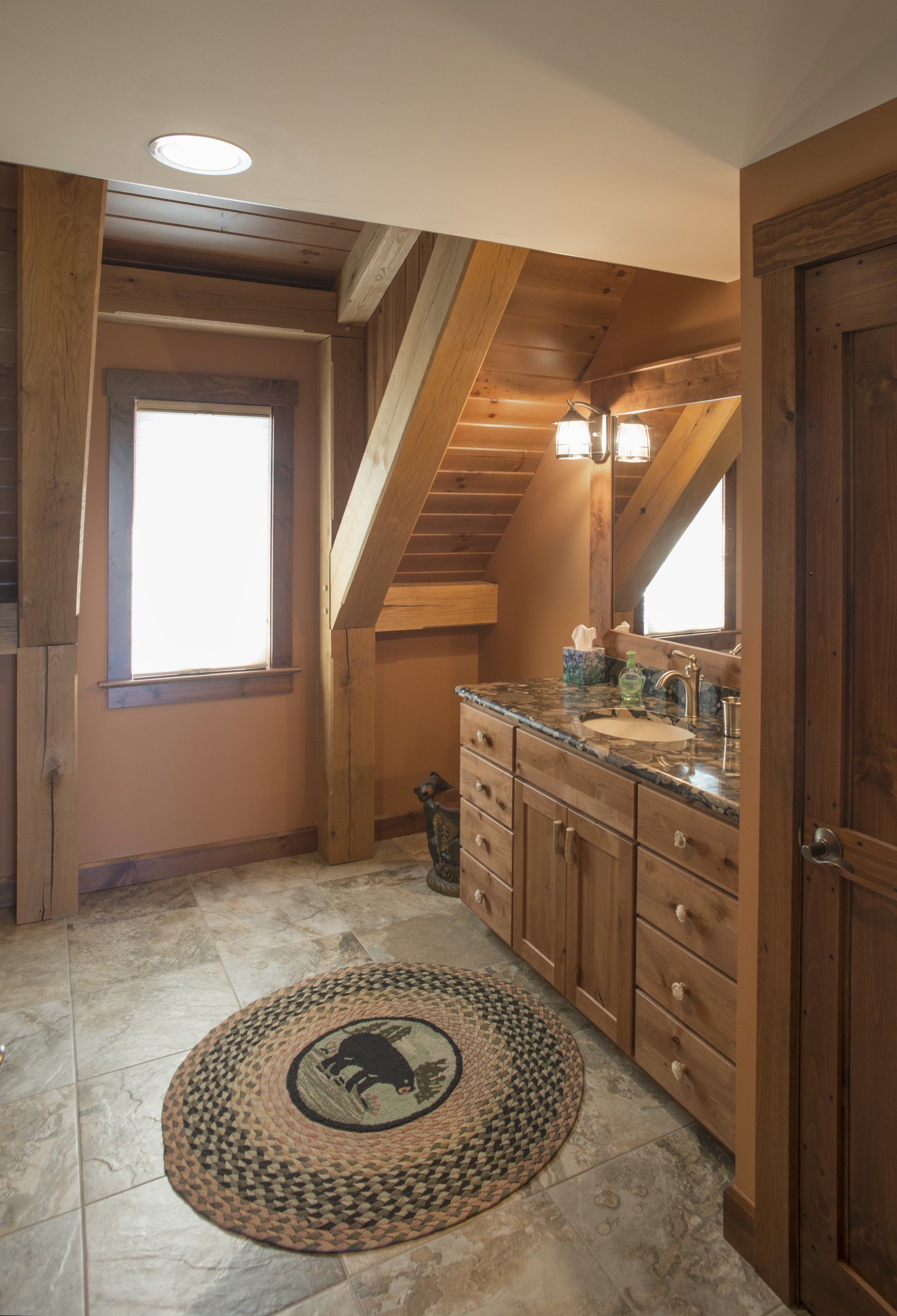 Rustic bathroom with wood beams, cabinetry, and a round rug featuring a buffalo.
