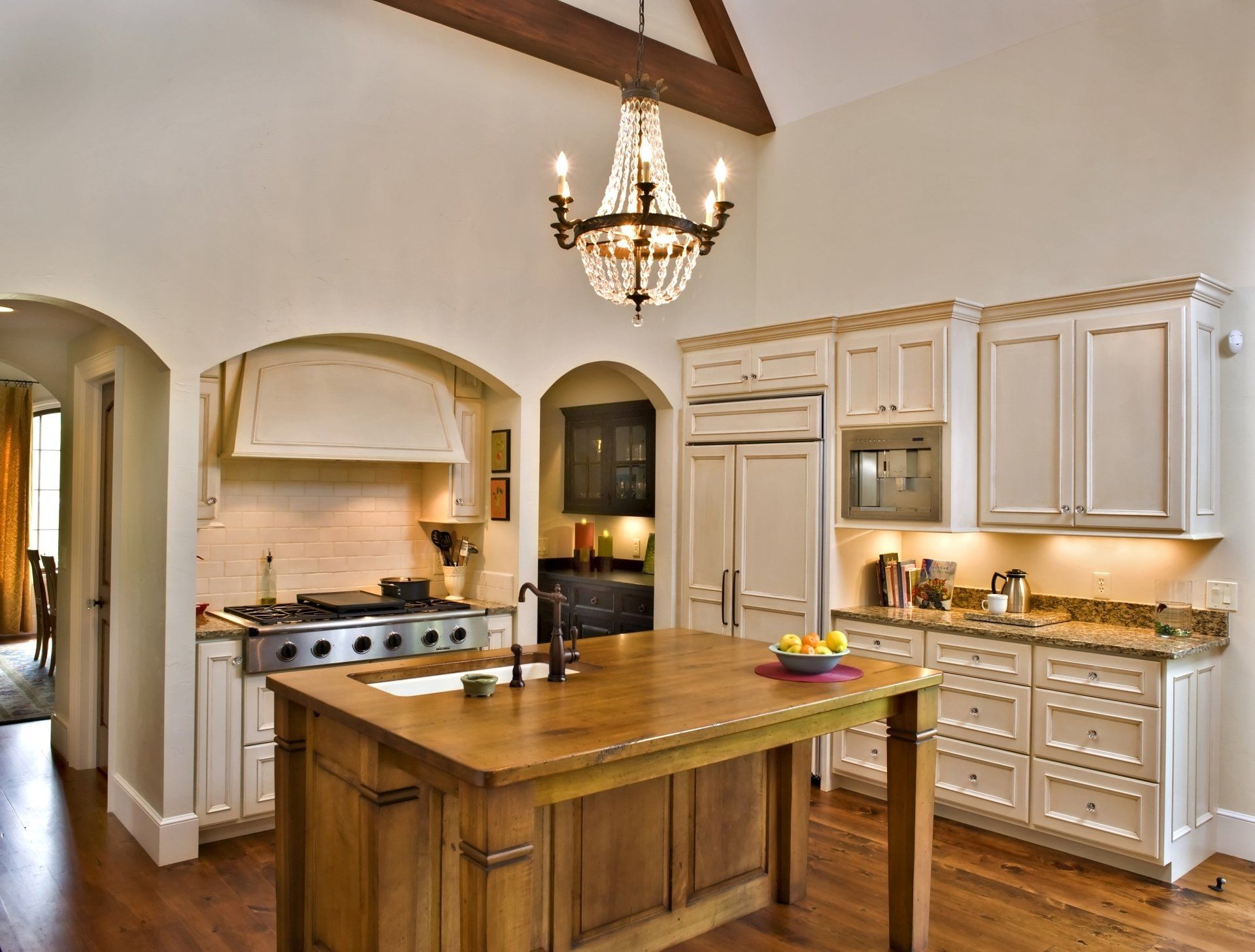 Kitchen with wooden island, cream cabinets, and a chandelier.