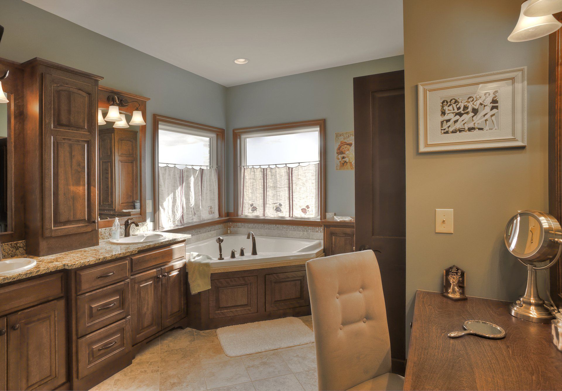 Bathroom with wood cabinets, tub, windows, and vanity with mirror.