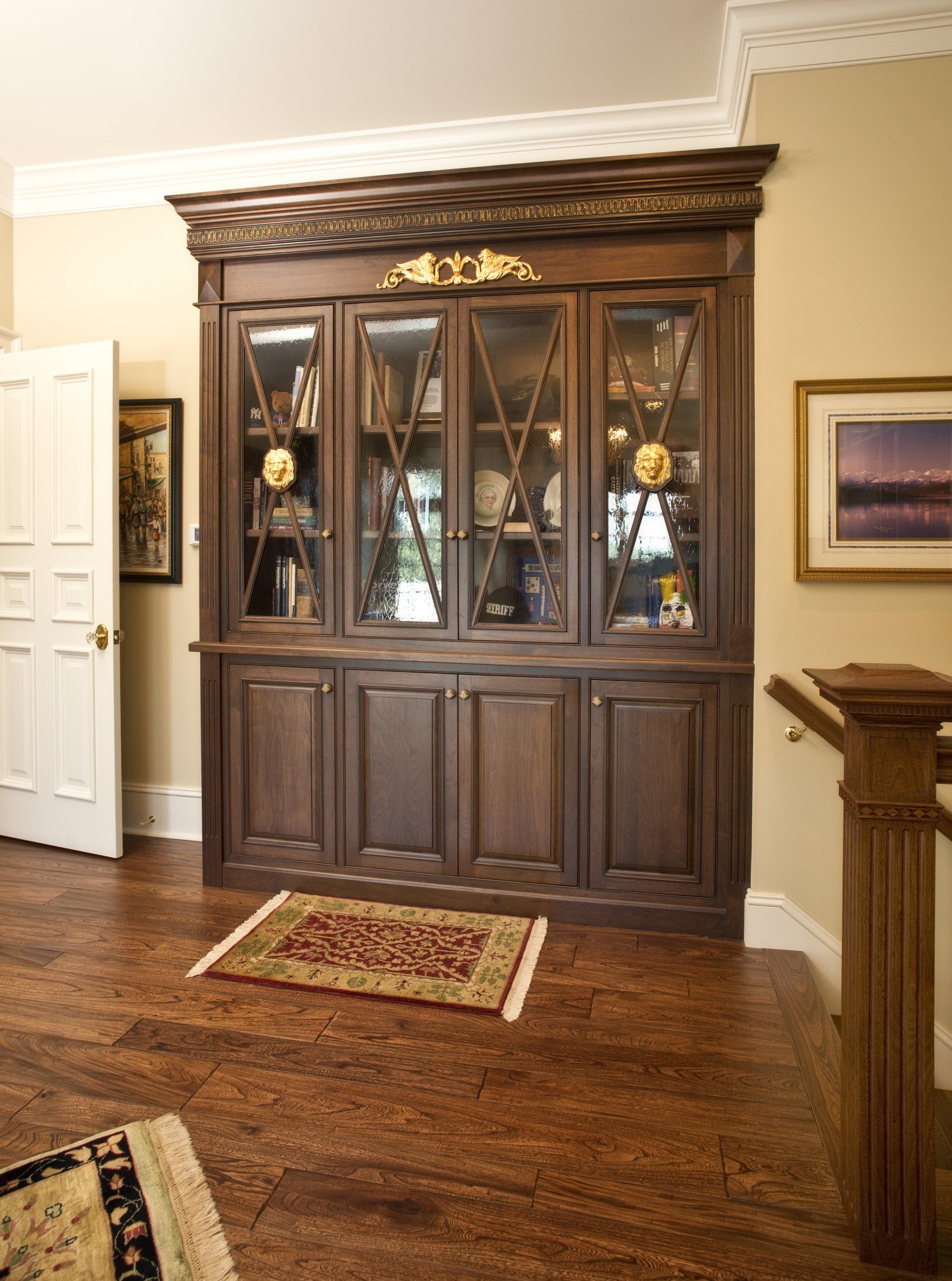 Dark wooden cabinet with glass doors, holding objects, on a patterned floor, and a small rug.