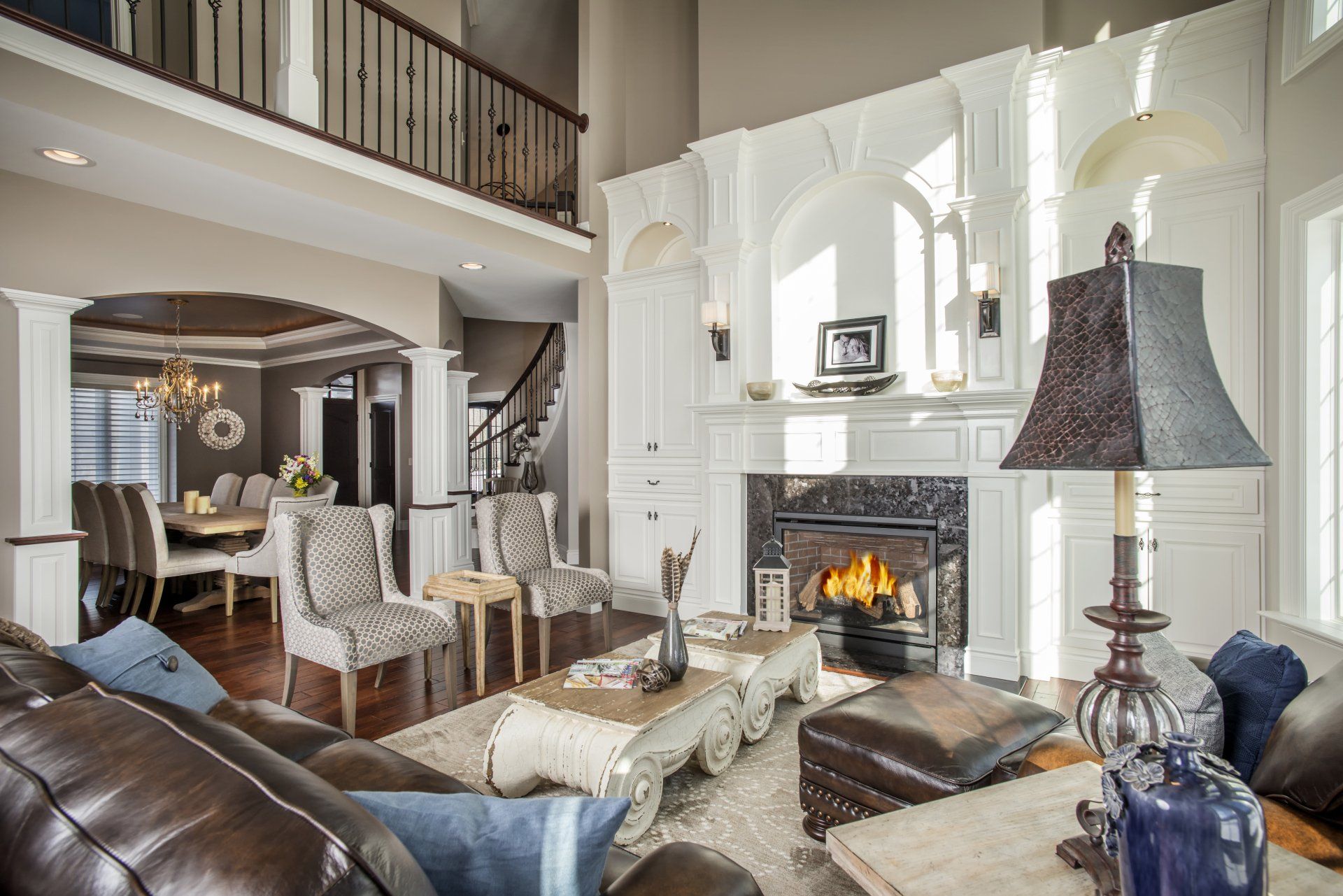 Spacious living room with a fireplace, leather sofa, and dining area visible in the background.