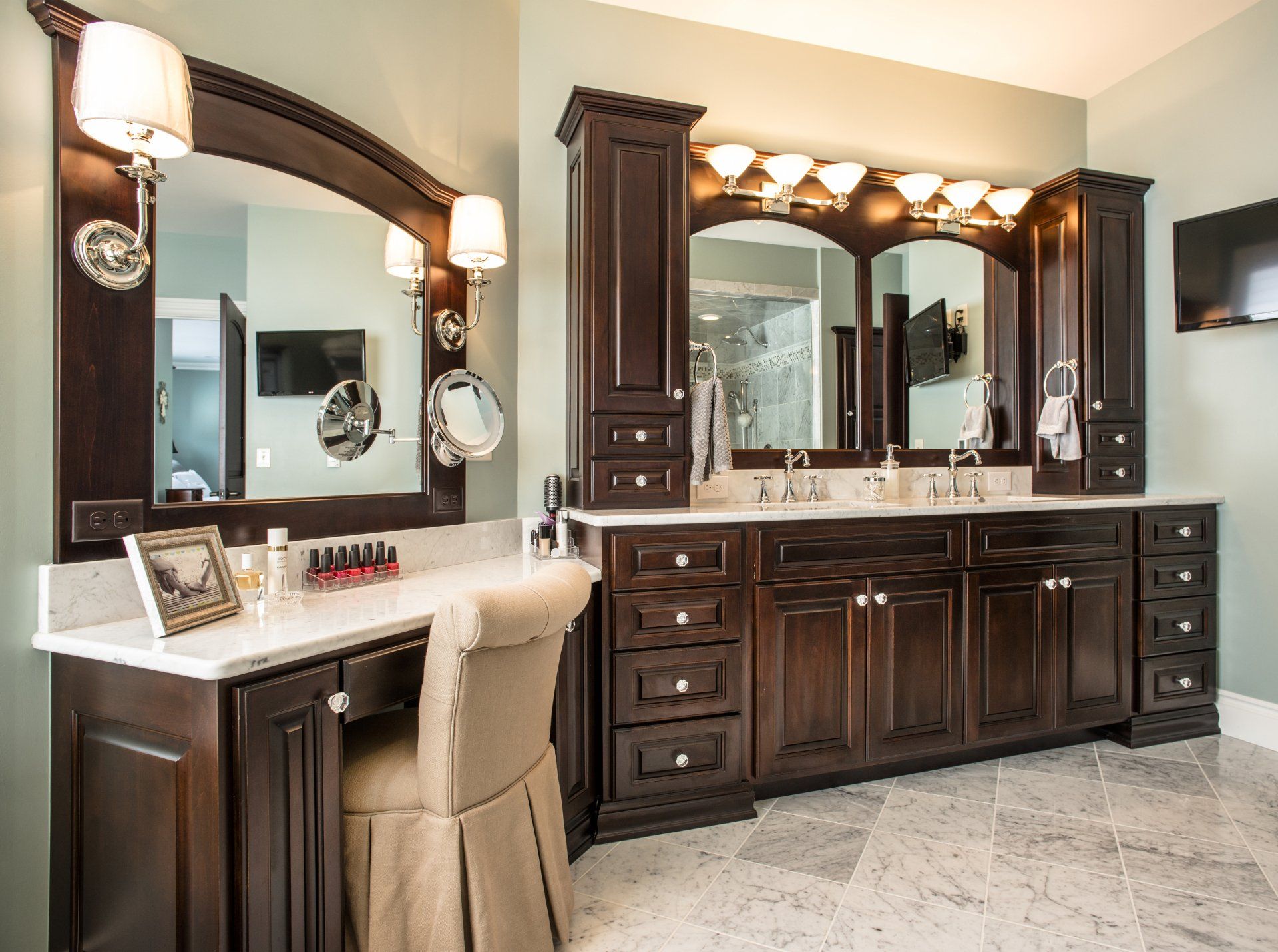 Bathroom with dark brown vanity, two sinks, large mirrors, and makeup area.