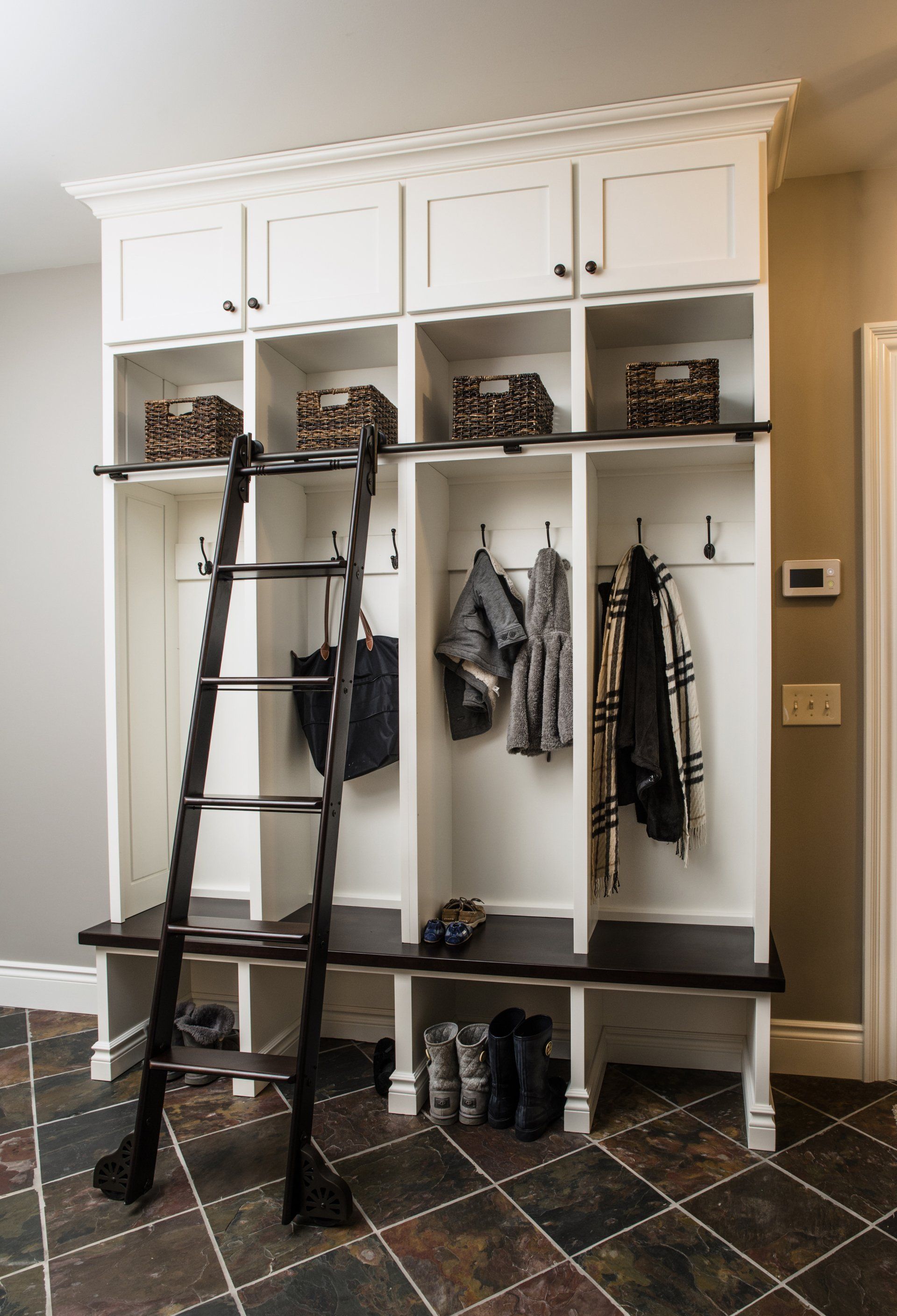 A mud room with a small ladder and lots of shelves featuring hooks. 