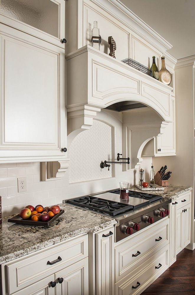 A kitchen with white custom cabinets and a stove top oven.