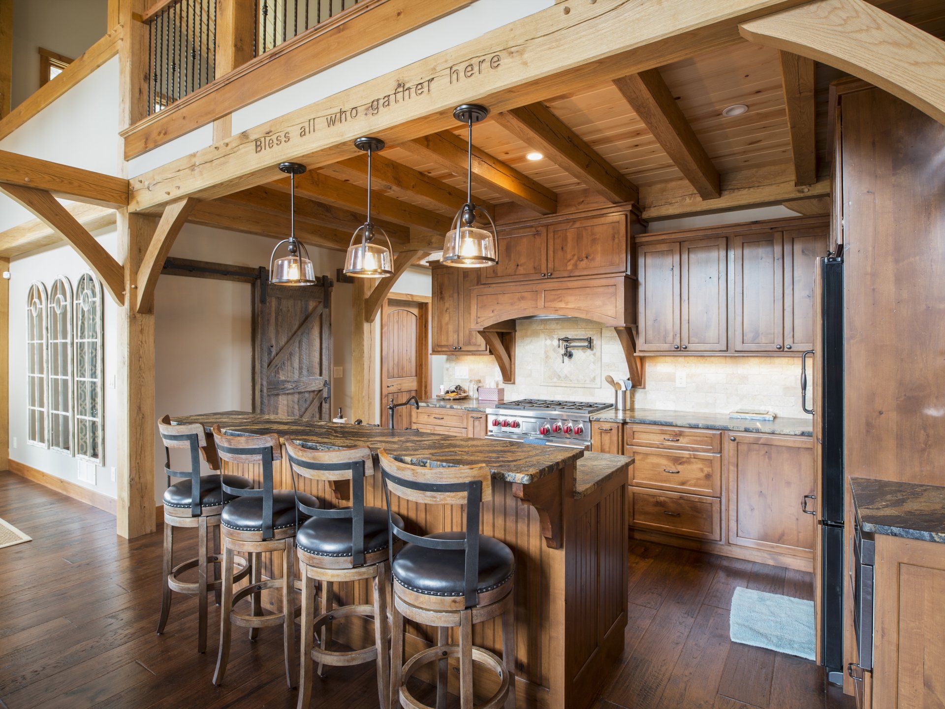 Rustic kitchen with wood beams, island with stools, and pendant lights.