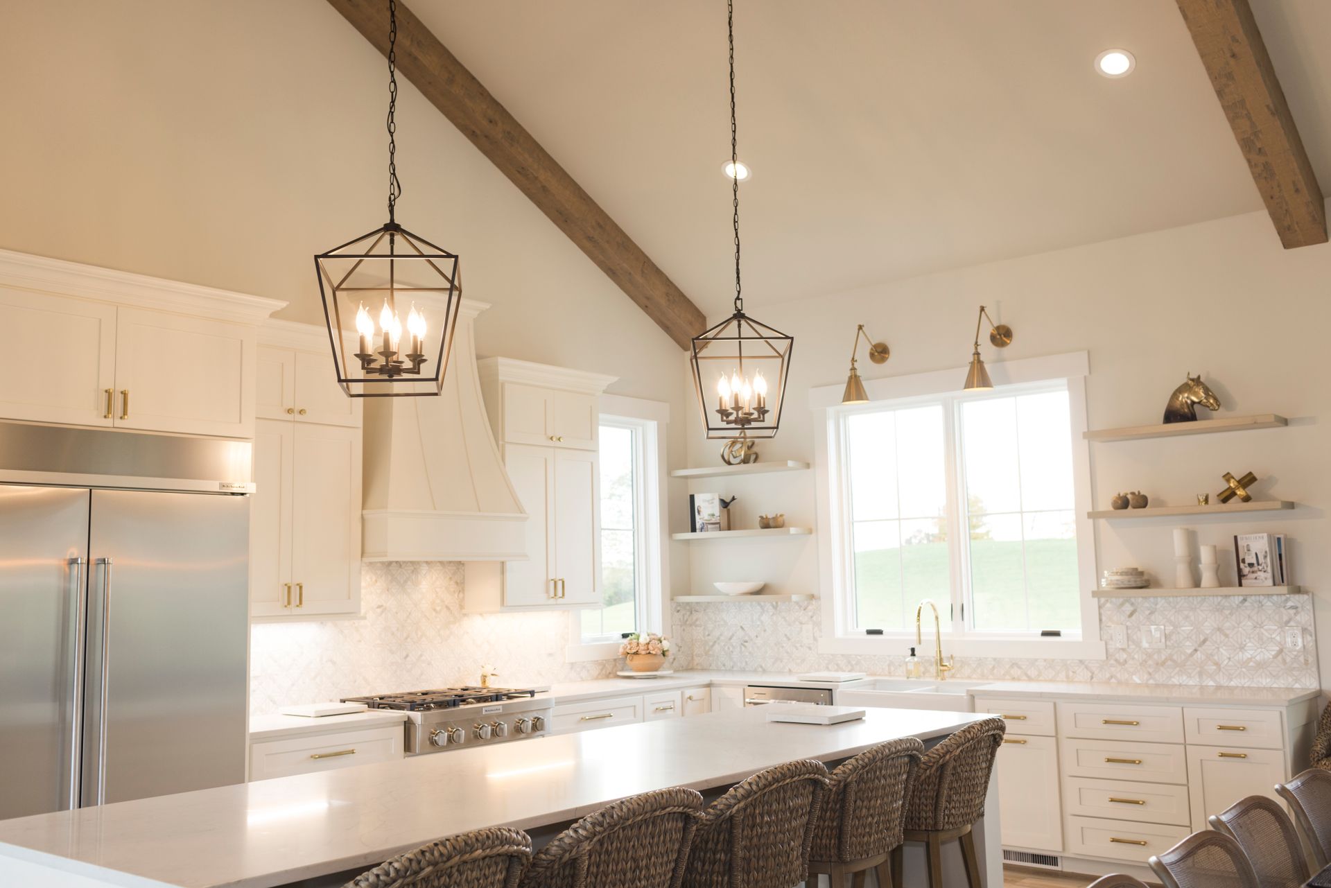 White kitchen with island, stainless steel appliances, and pendant lights.