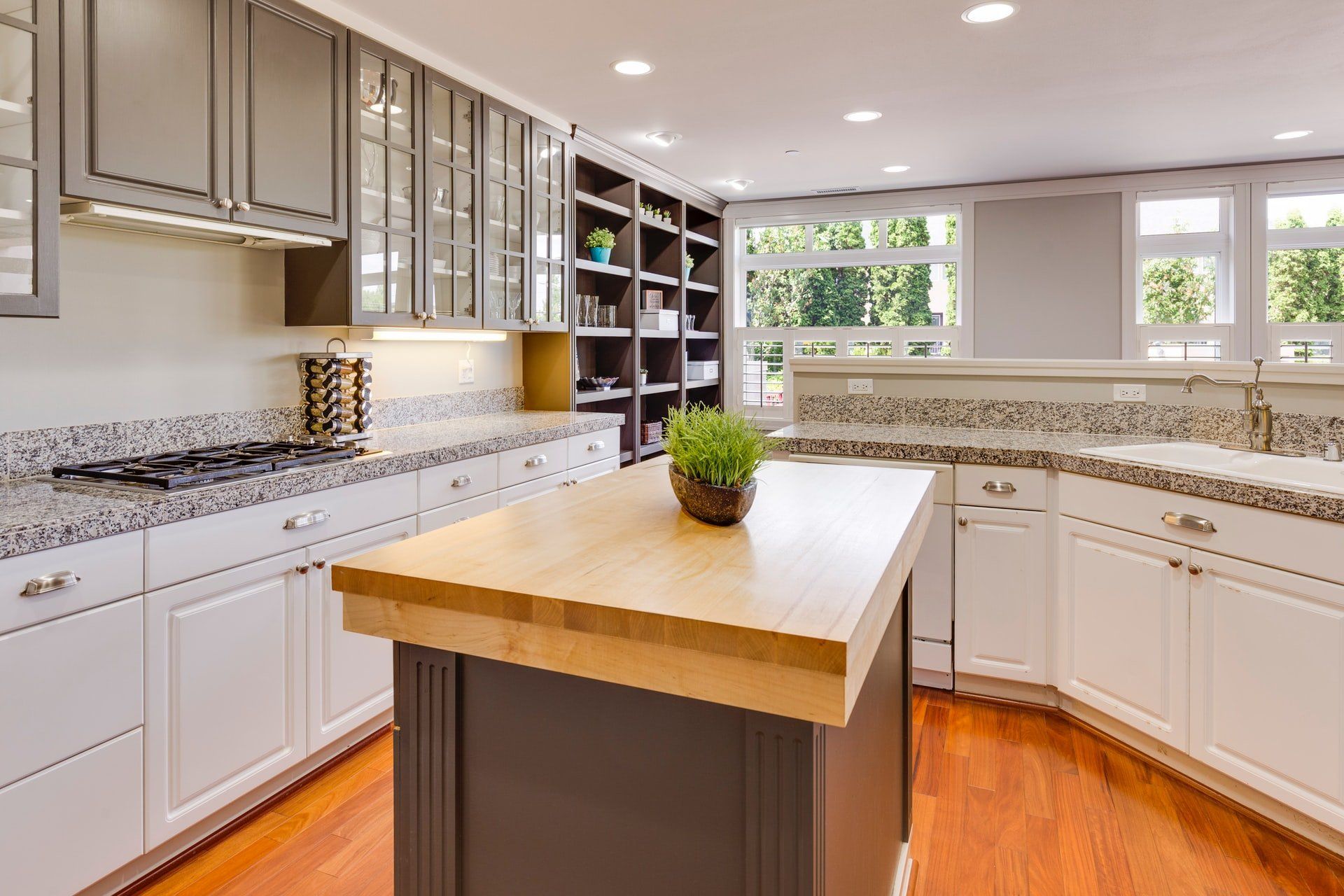 There is a large island in the middle of the kitchen featuring beautiful white custom cabinetry. 
