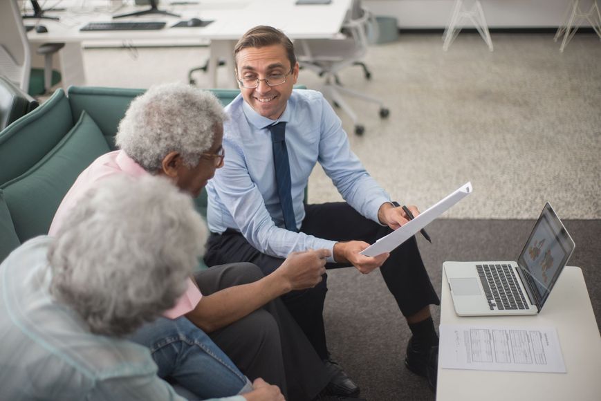 Man showing a document to two coworkers during a laptop meeting in a bright office lounge