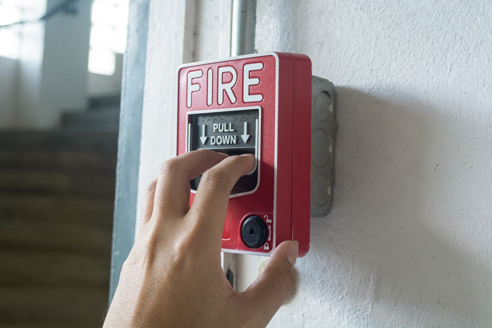 Individual pressing a fire alarm button, promoting Harford Alarm Co. Residential Fire Protection Sys