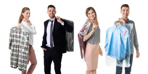 Quatre personnes tenant des vêtements propres et souriant à la caméra. Fond blanc.