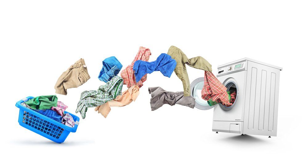 Panier à linge avec des vêtements volant dans une machine à laver sur fond blanc.