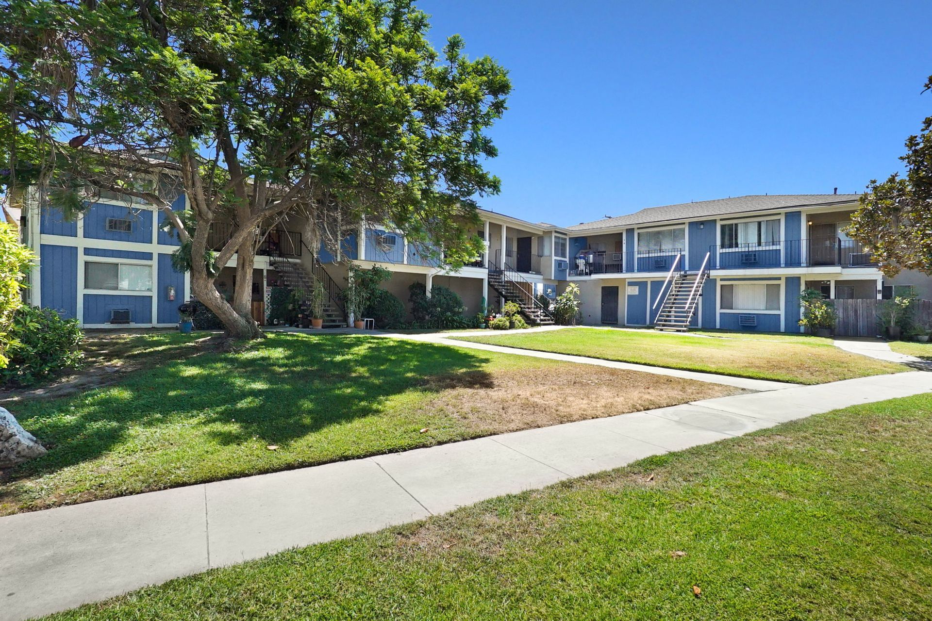 A row of apartment buildings with a sidewalk in front of them