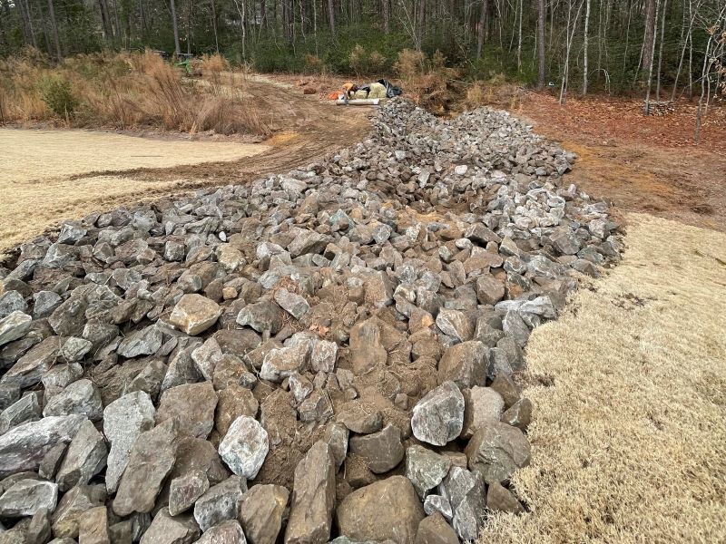 A pile of rocks and dirt in a field with trees in the background.